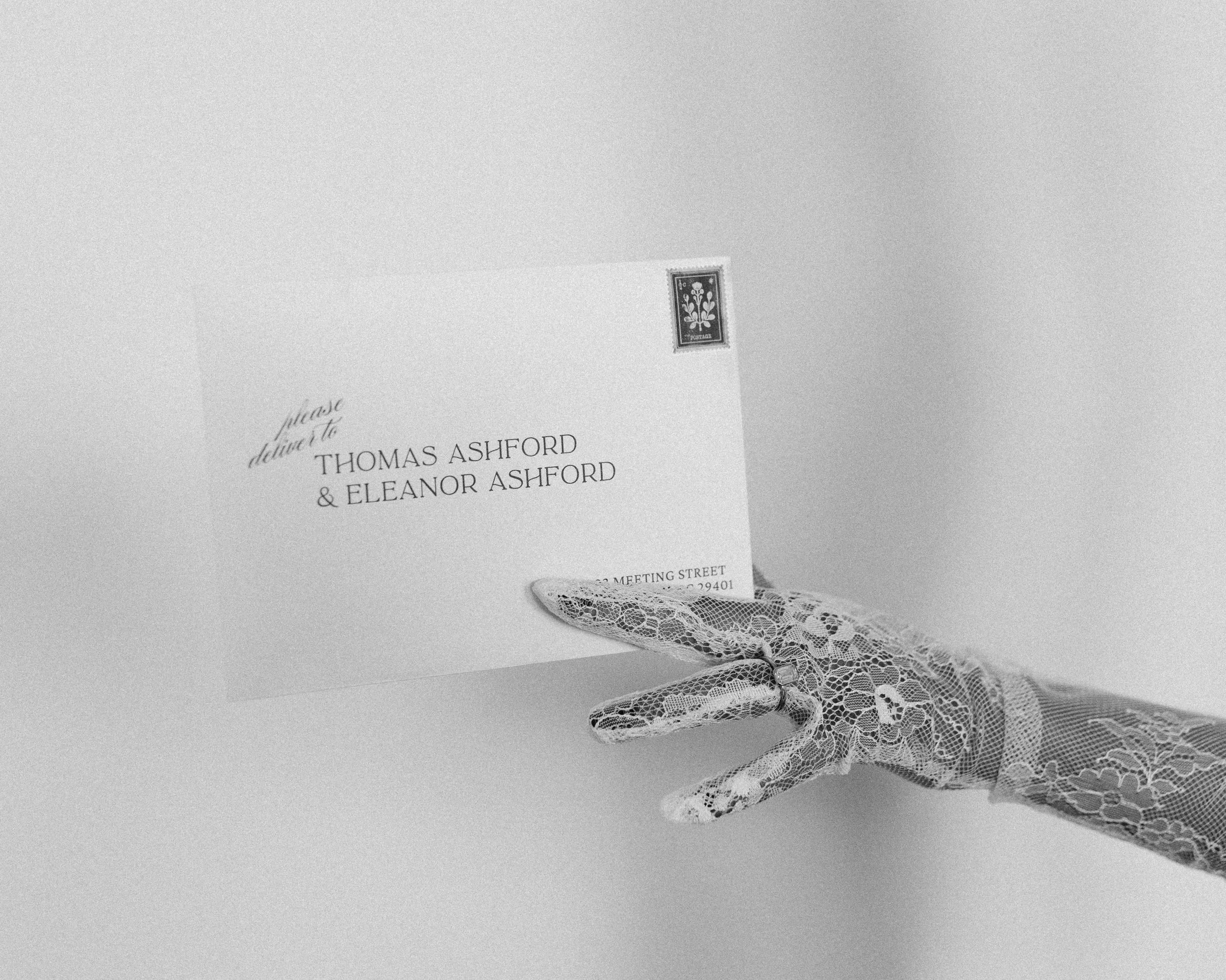 A wedding invitation, a postage stamp, and a white lace glove.