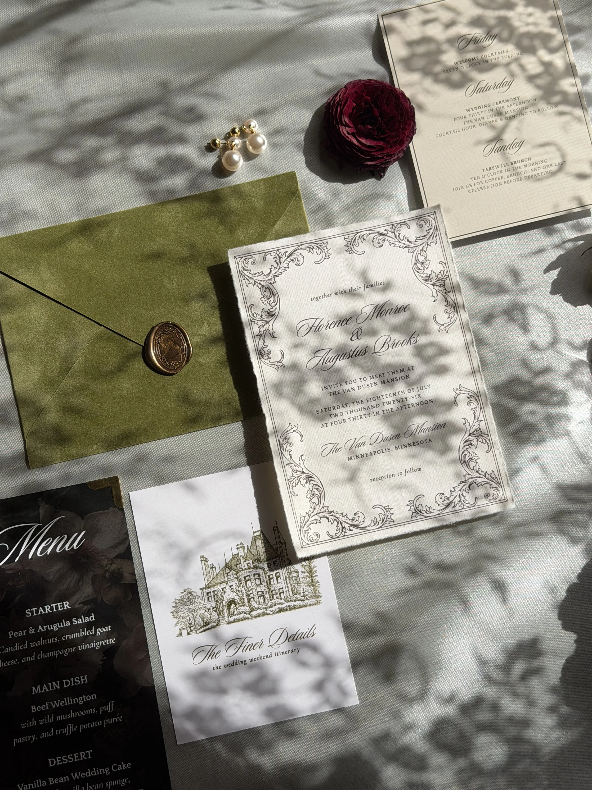 Wedding or event schedule and details for a wedding weekend at The Van Dusen Mansion in Minneapolis, Minnesota, with decorative floral design, and a green envelope with a wax seal, a dark red flower, and pearl earrings placed on a light-colored fabri