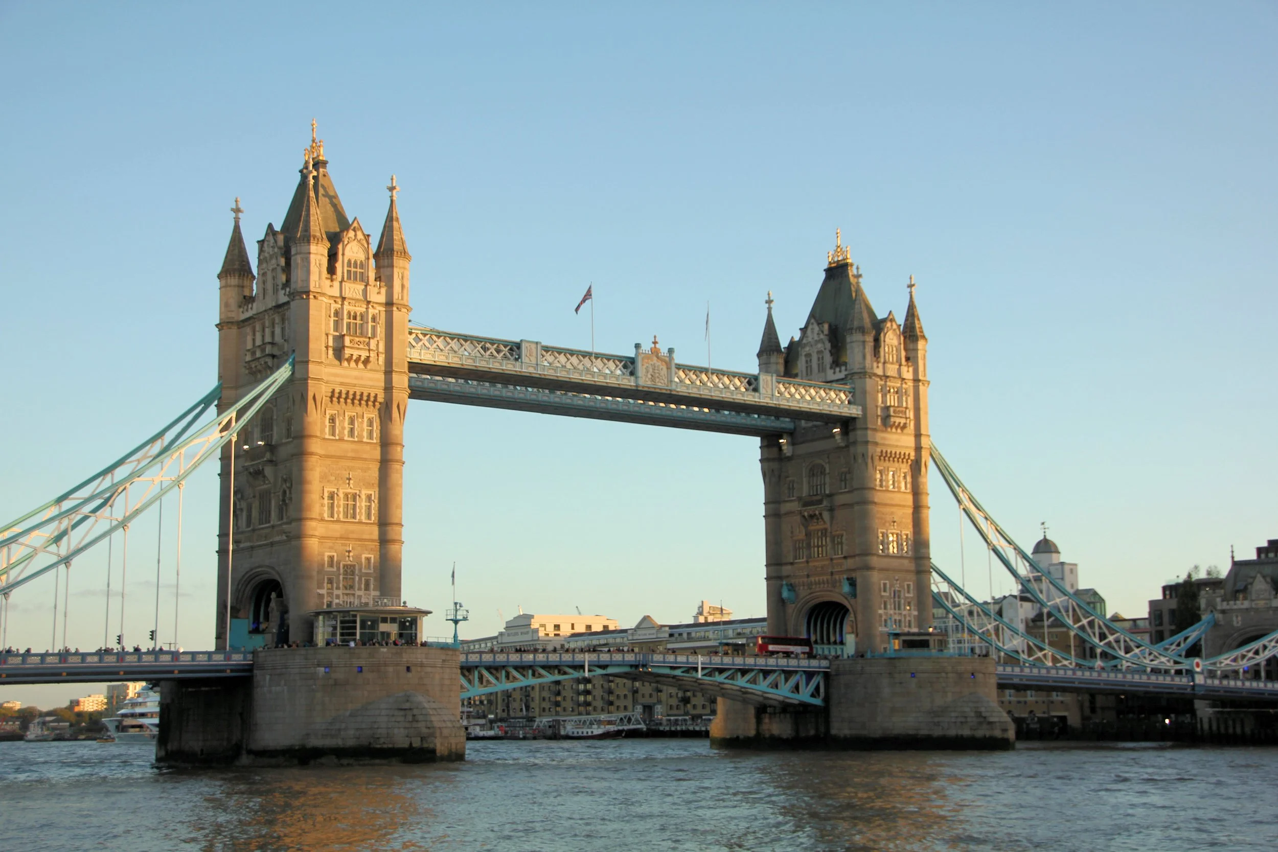 A view of Tower Bridge in London, showing its two towers and the bascule drawbridge over the River Thames in the late afternoon sunlight.