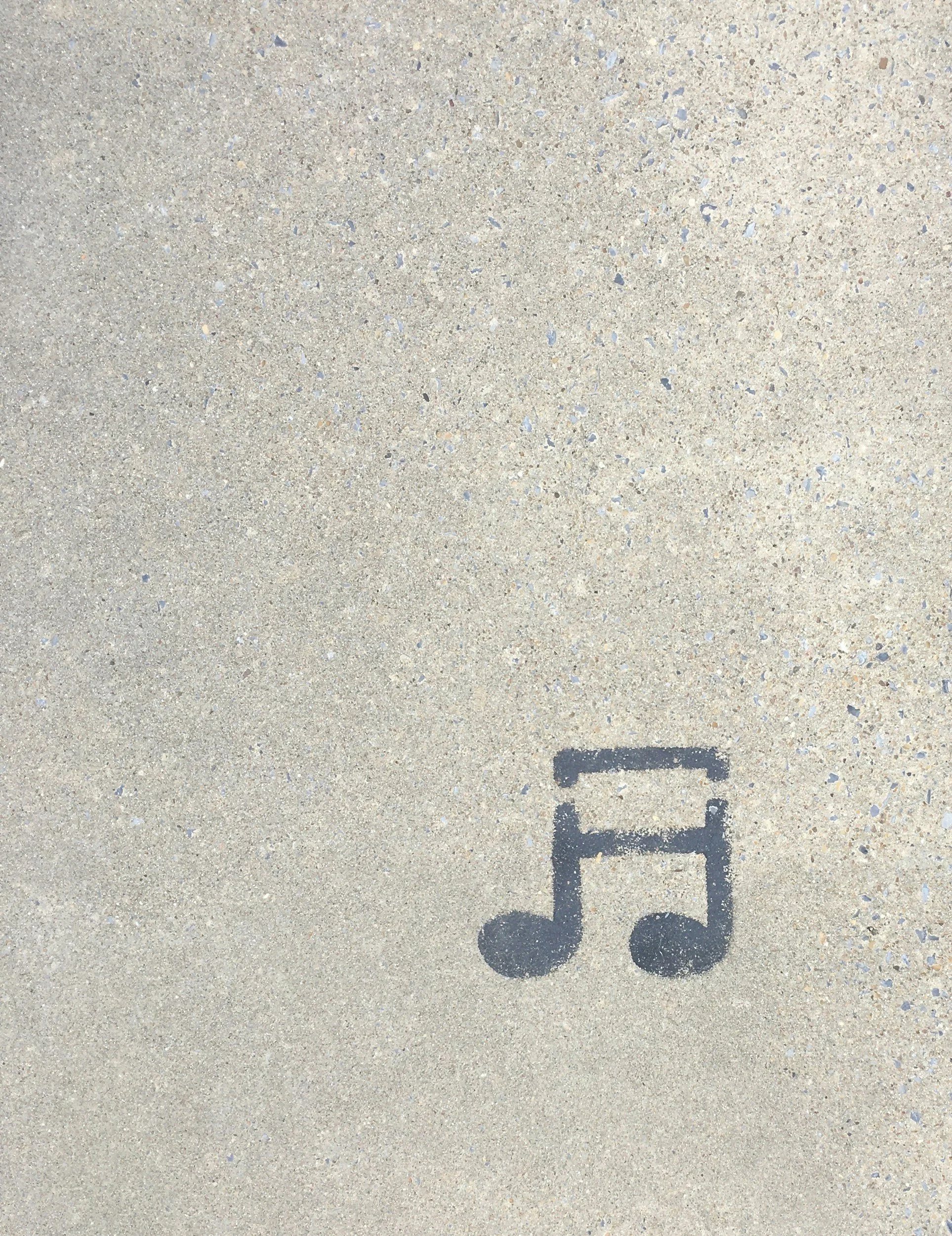 Shadow of a scooter painted on a concrete sidewalk.