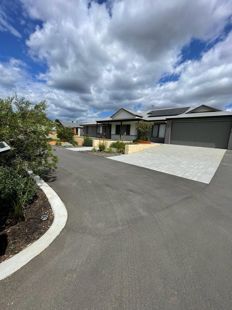 View of a suburban house with a driveway and landscaped front yard under a cloudy sky.