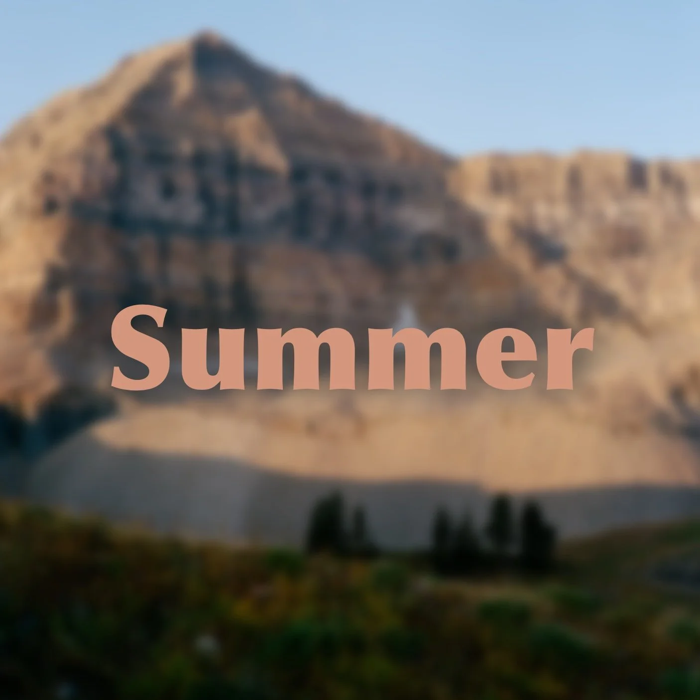 Blurred landscape featuring a mountain with buildings at the top and a few trees at the bottom, with the word 'Summer' written across the center.