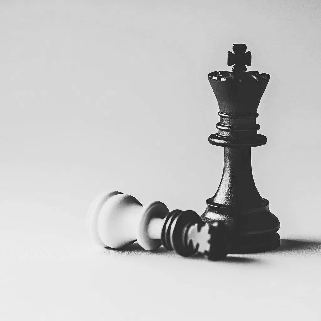 Black king chess piece standing upright next to a fallen white king chess piece on a plain surface.