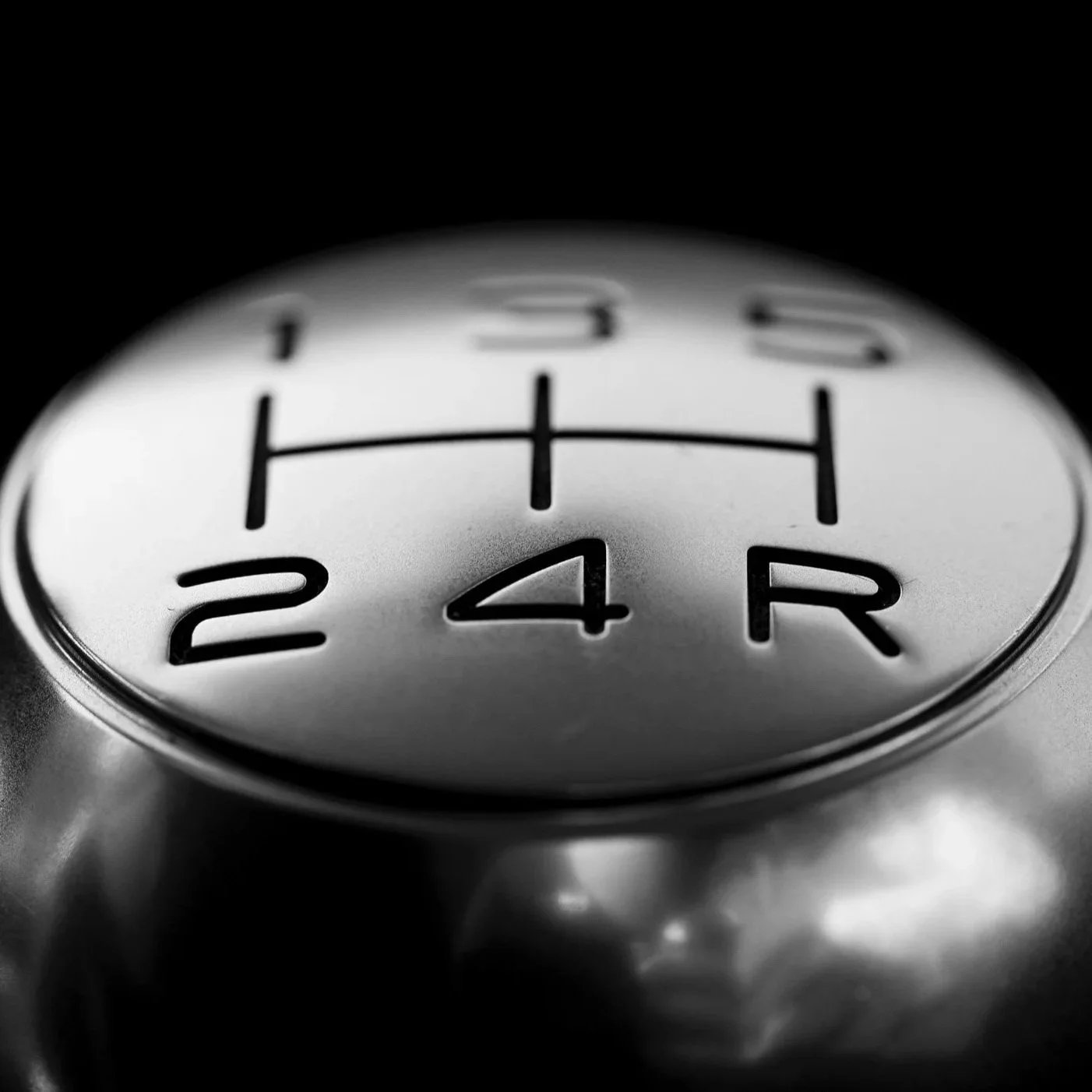 Close-up of a car gear shift knob showing reverse, neutral, and drive positions.