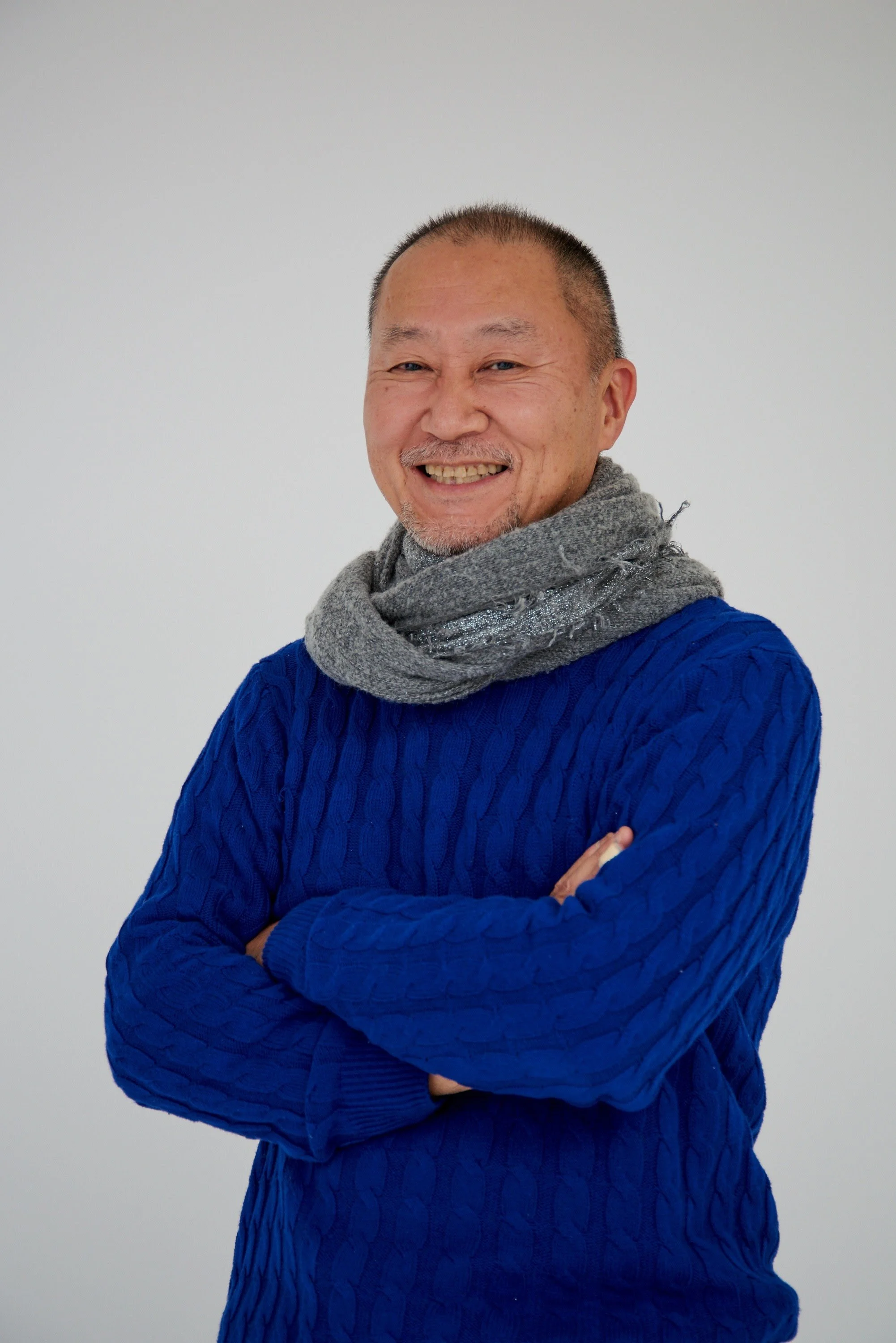 笑顔の中年男性、青いセーターと灰色のスカーフを着用、白い背景.