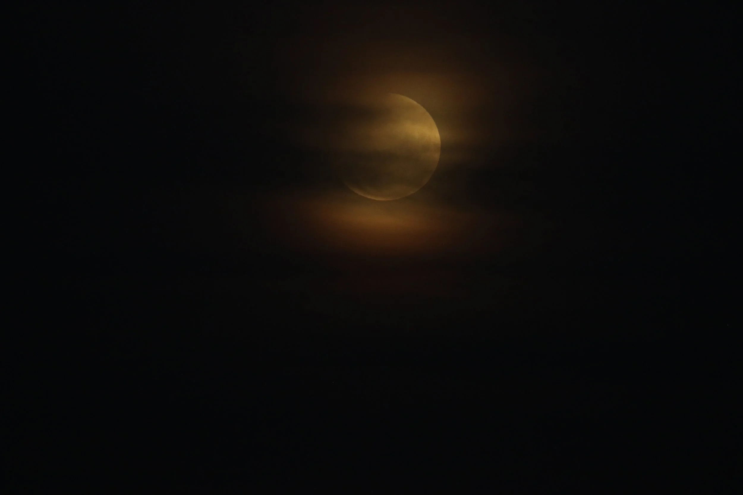 Crescent moon glowing through dark clouds