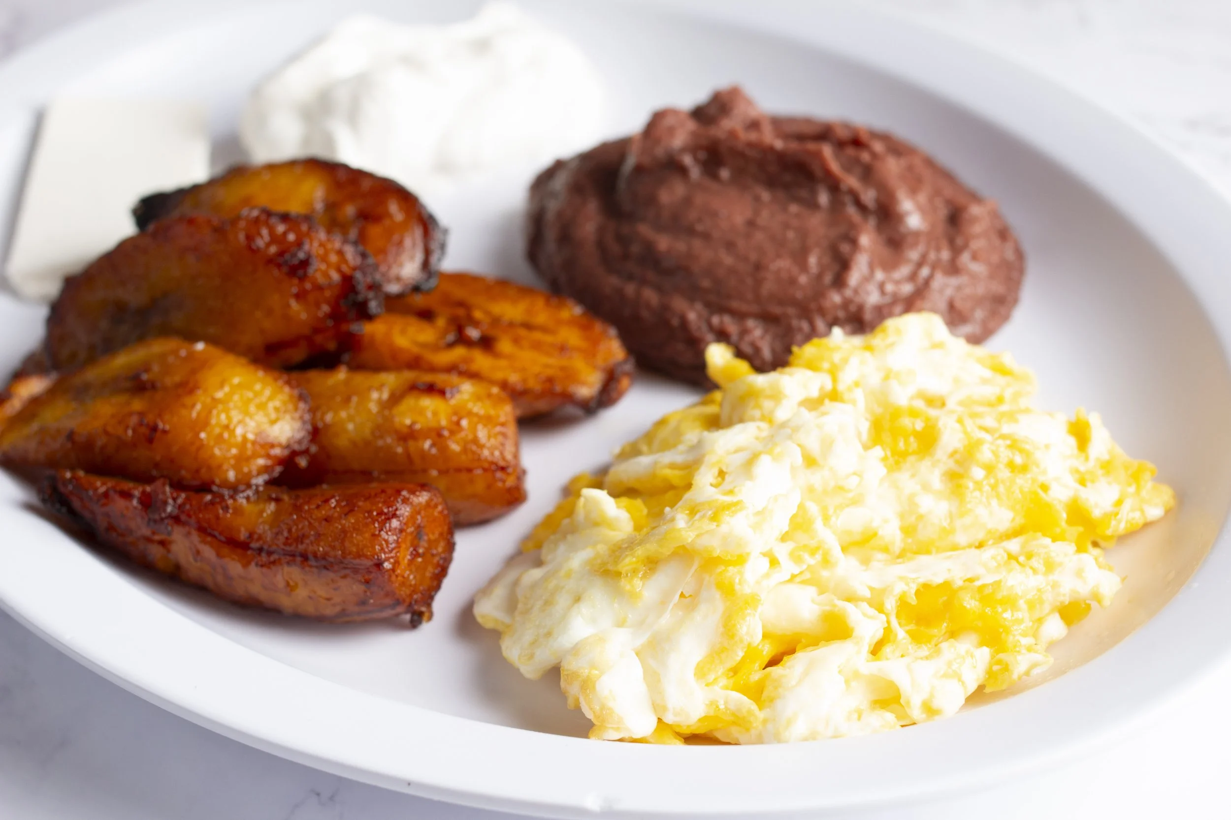 Salvadoran style breakfast with eggs, beans, fried plantain and sour cream.