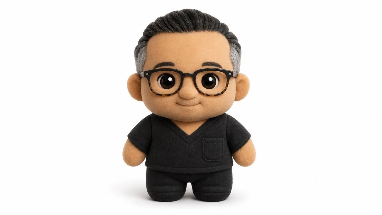 Cute plush doll of Dr Raj Menon with glasses, black scrubs, and gray hair, standing on a white background.