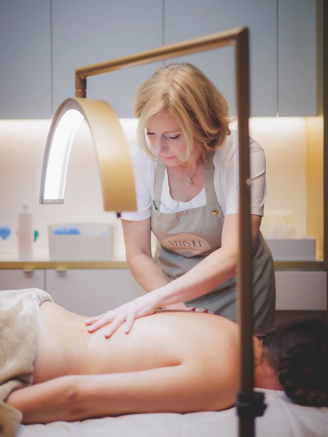 Een masseur geeft een rugmassage aan een persoon die op een massagetafel ligt in een rustige ruimte.