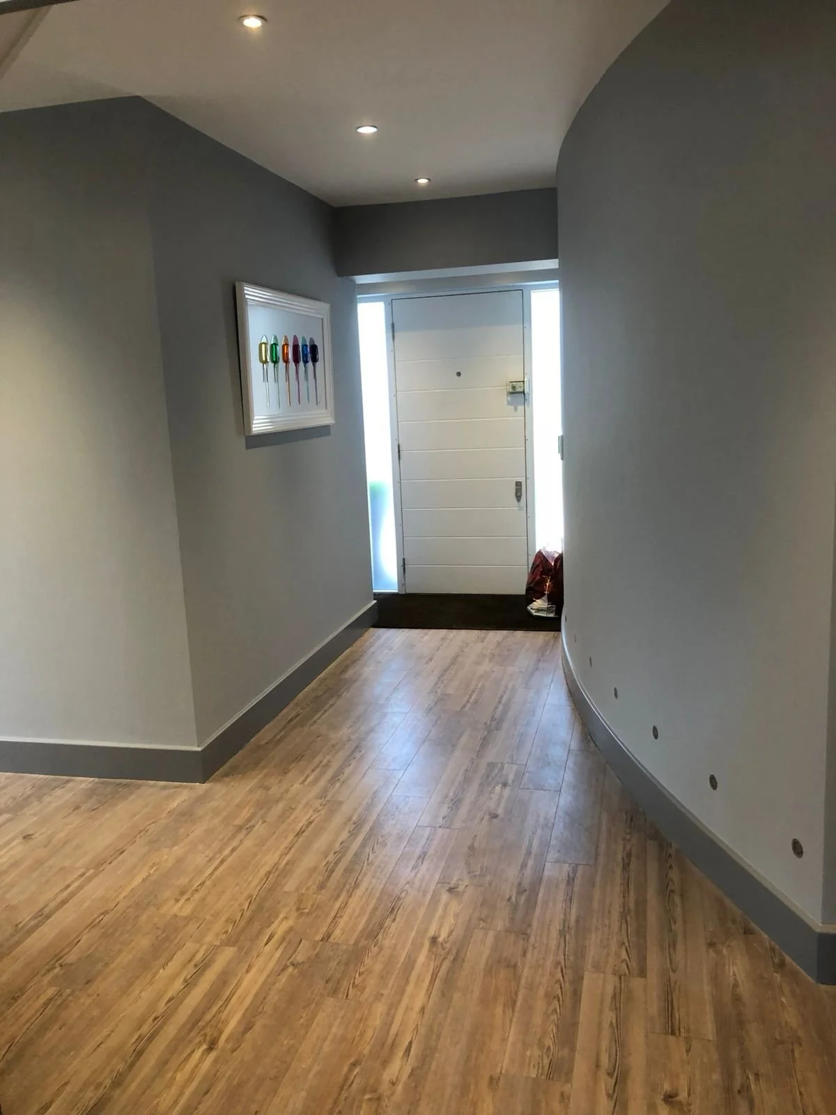 Entryway with wooden floor, white door, and gray walls, decorated with a framed picture of colorful popsicles.