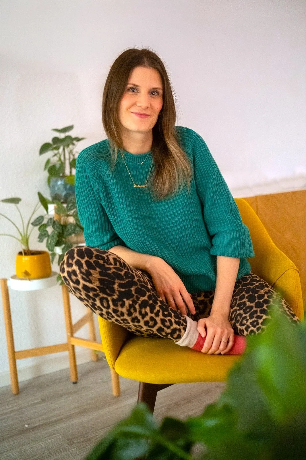 Steph sitzt auf einem Stuhl und lächelt in die Kamera