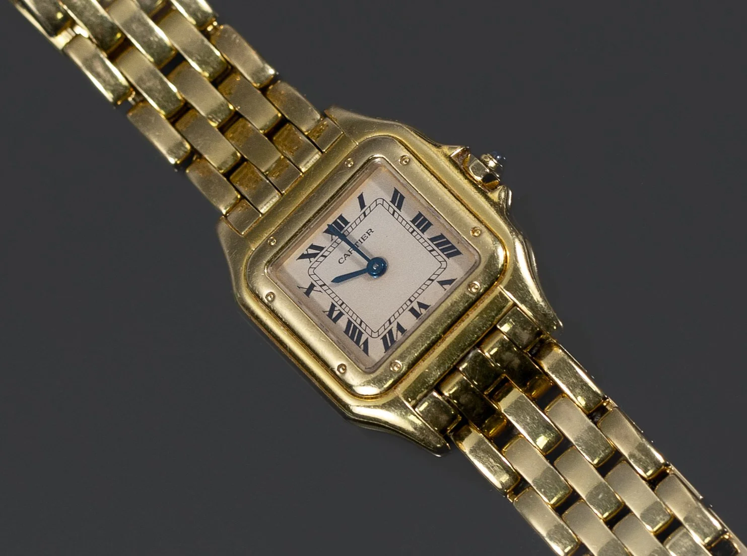 A gold Cartier wristwatch with a square face, Roman numeral hour markers, and a gold metal bracelet.