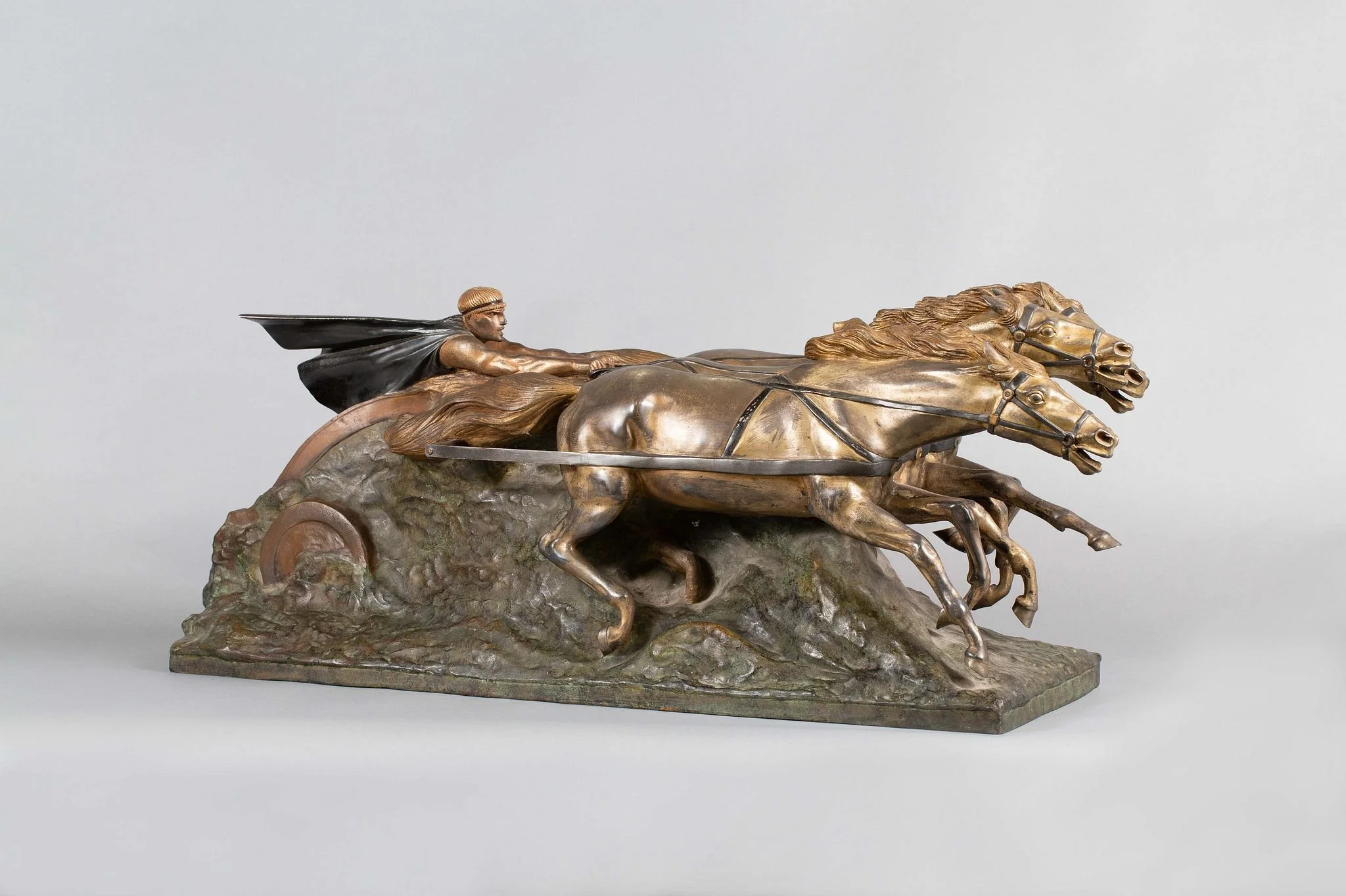 Bronze sculpture of a chariot drawn by two horses with a driver in a cape, set on a textured base.