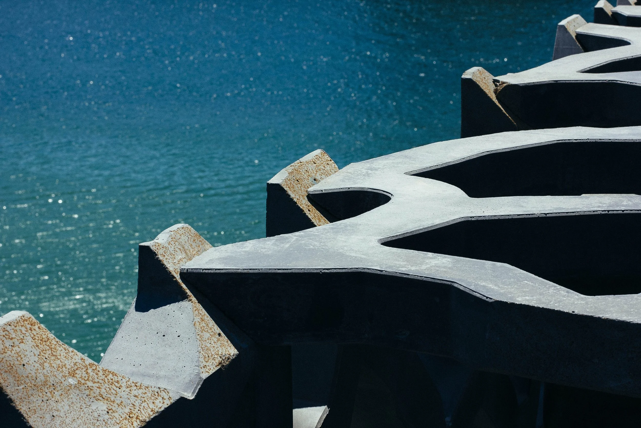 Close-up view of concrete breakwater structures with curved openings, extending into a body of water.