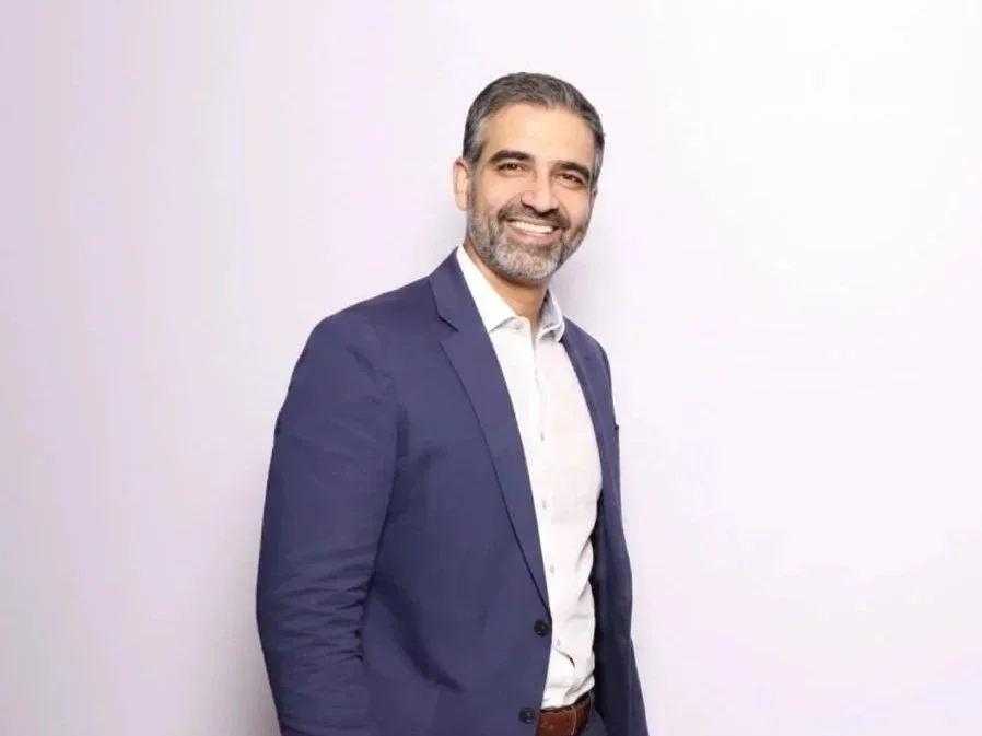 Portrait photo of a man Hammad Mian in a pale blue shirt against green foliage