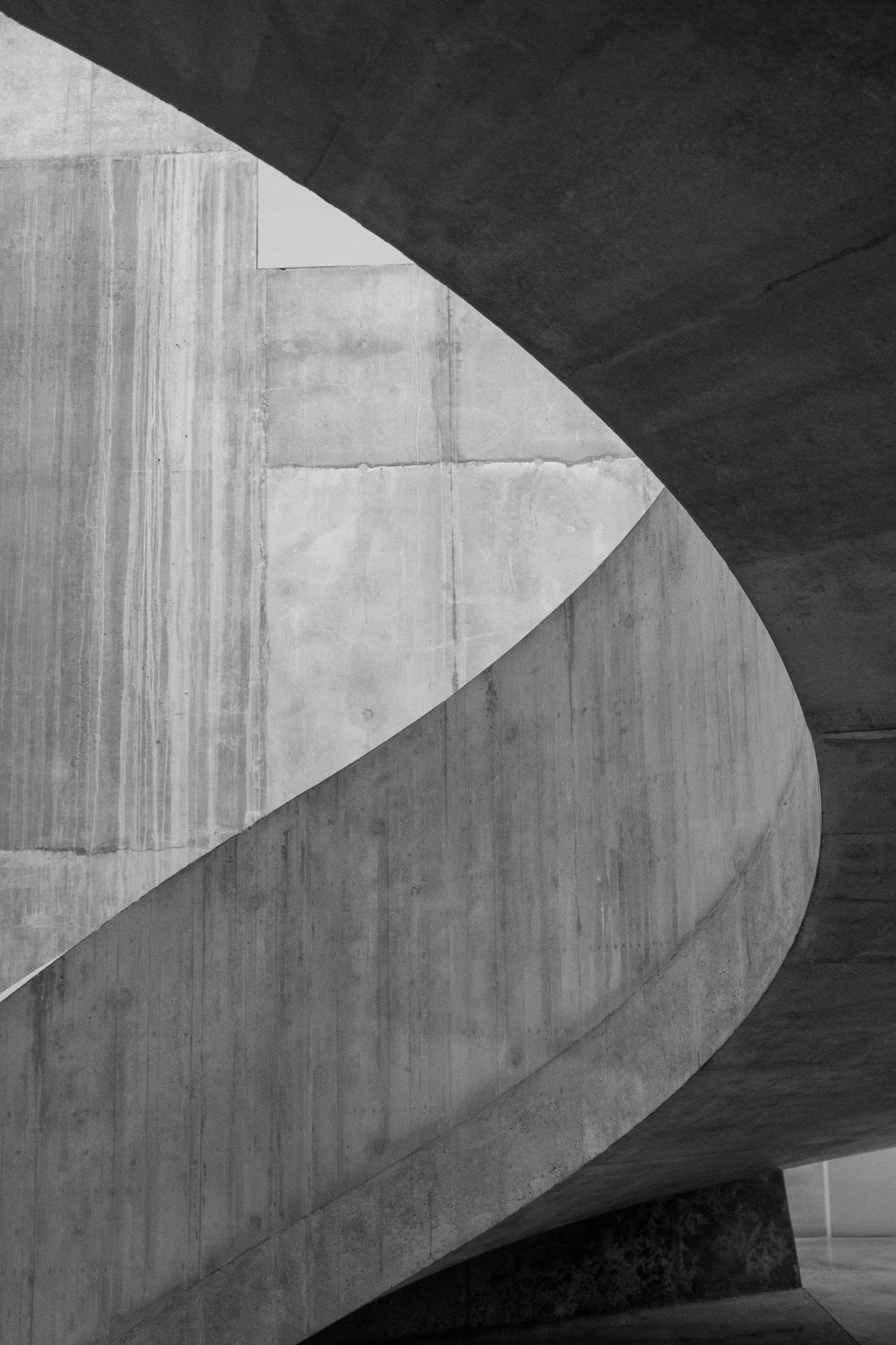 Abstract black and white architectural photograph of curved concrete walls and surfaces.