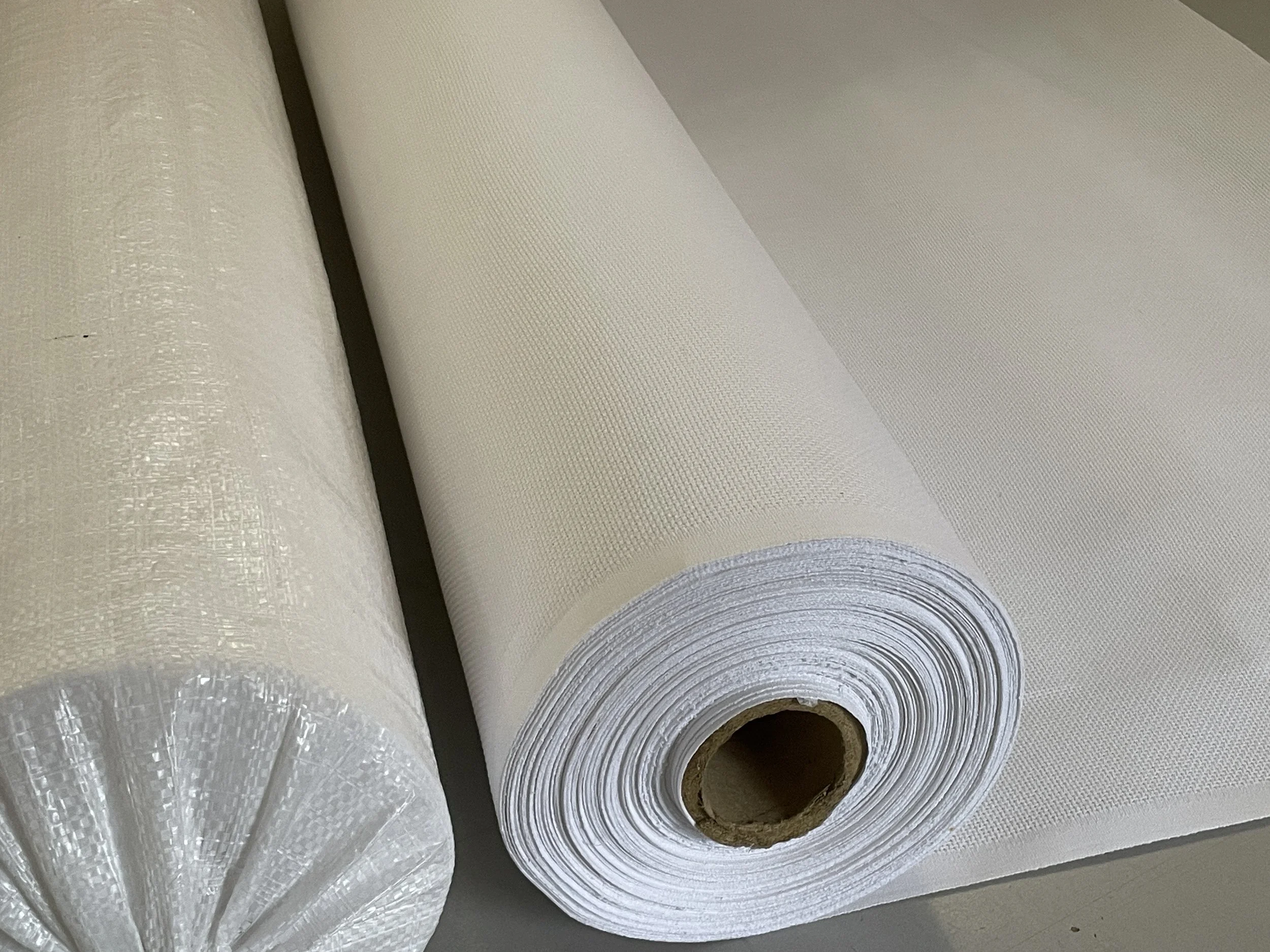 Close-up of two rolls of white textured wallpaper on a gray surface.