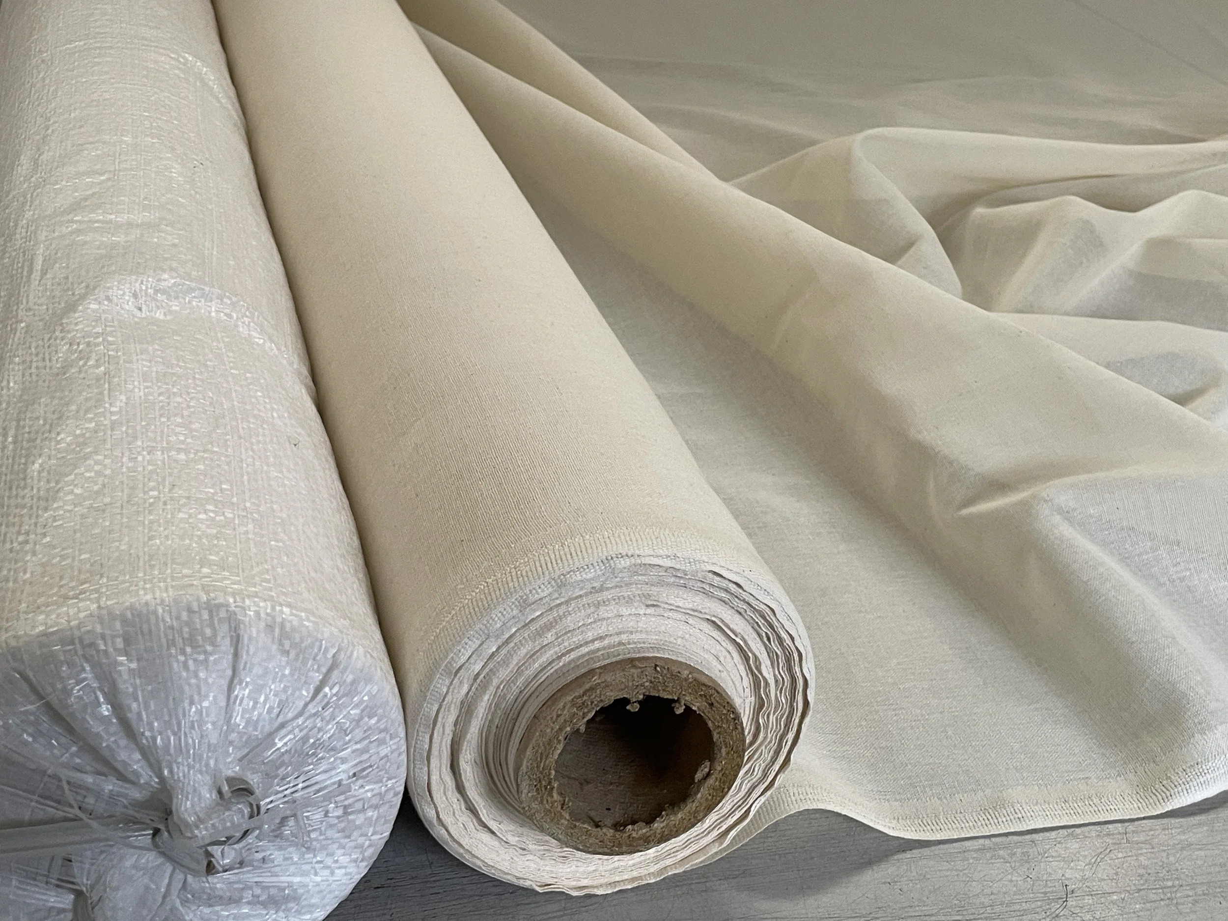Three rolls of fabric, with one partially unrolled, lying on a surface.