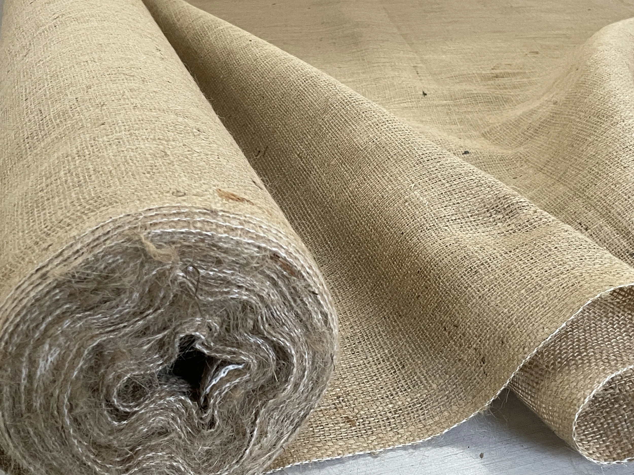 Close-up of a roll of burlap fabric unrolled on a surface.
