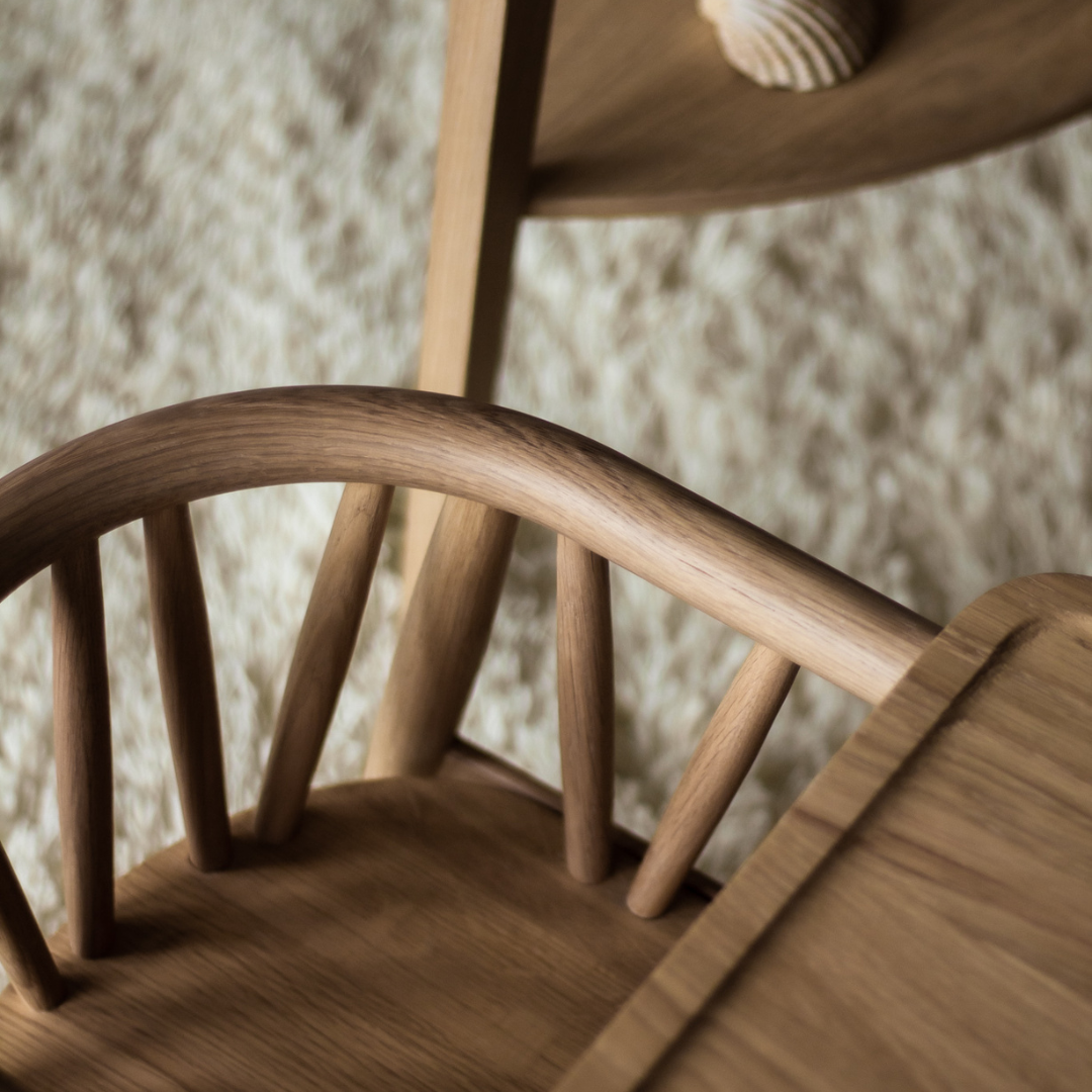 Nærbillede af en træstol med buede rygstøtte og lodrette spiler, set oppefra.