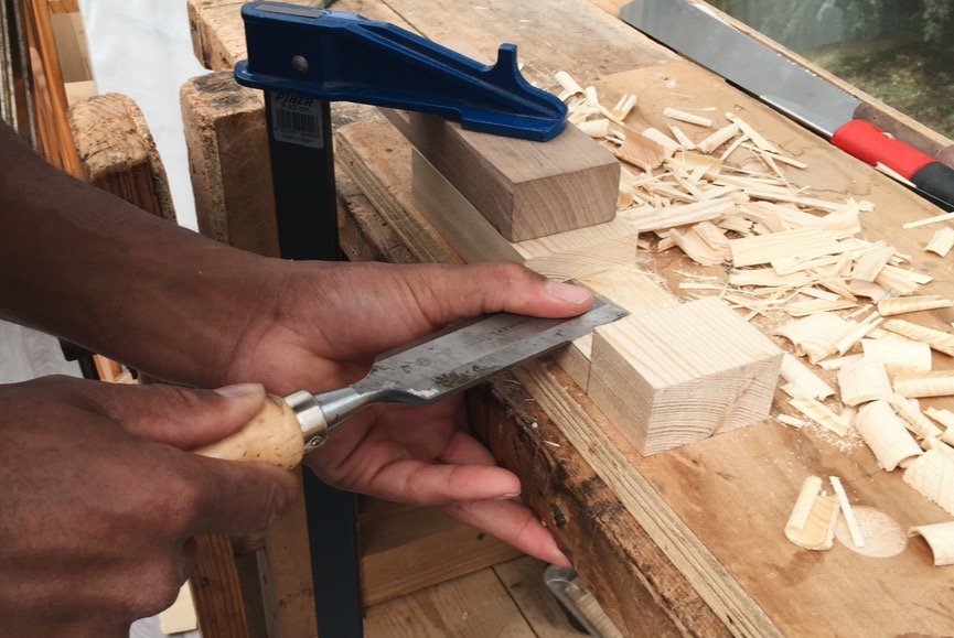 Une personne scie un morceau de bois dans un atelier de menuiserie.