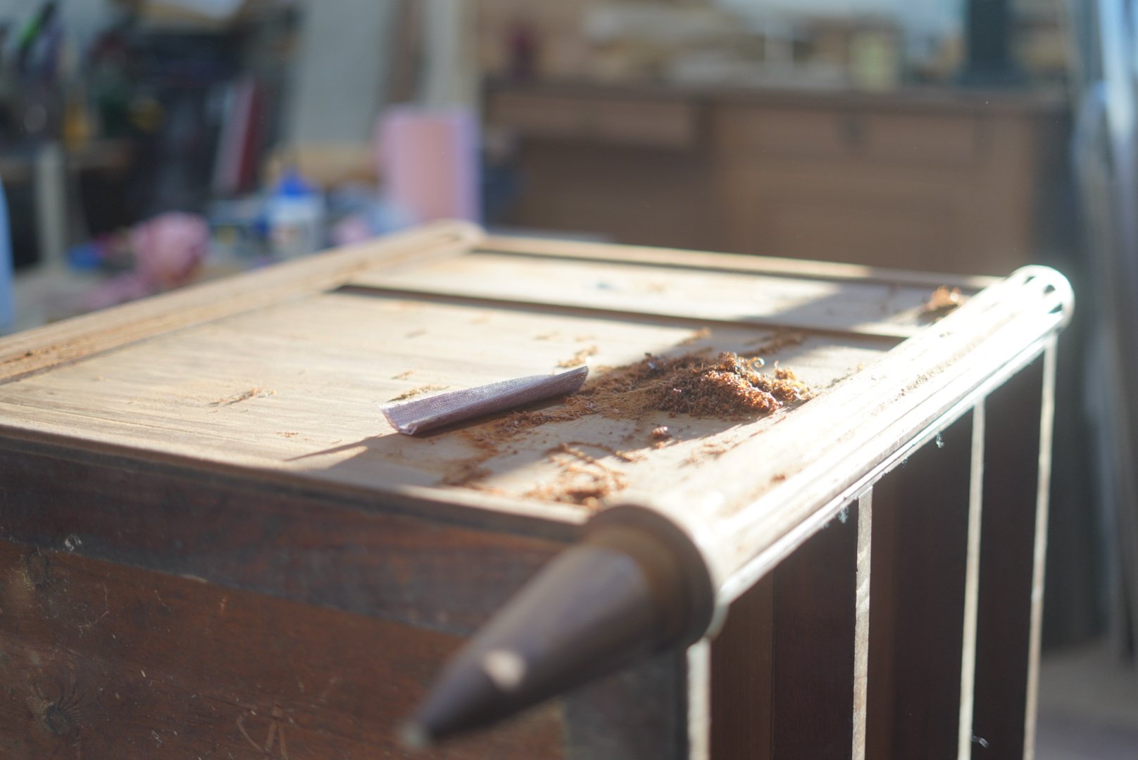 Une table en bois avec de la poussière et un chiffon, éclairée par la lumière naturelle, dans un atelier ou un garage.
