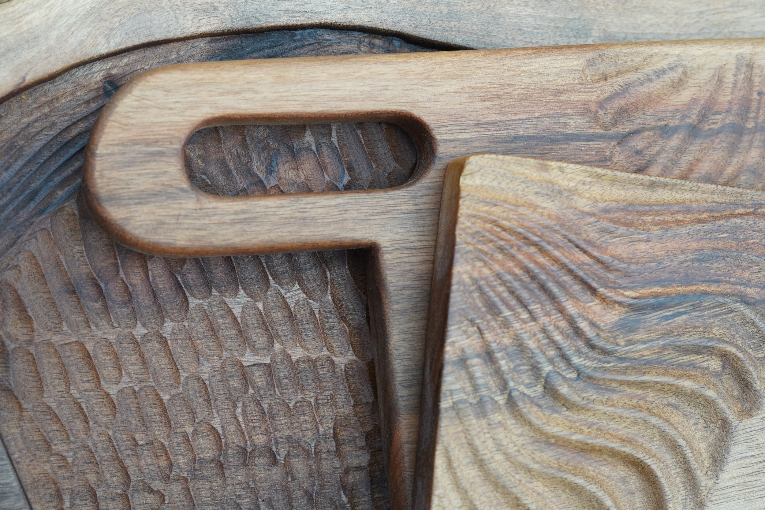 Détails en bois sculpté, montrant différentes textures et motifs dans deux couleurs de bois.