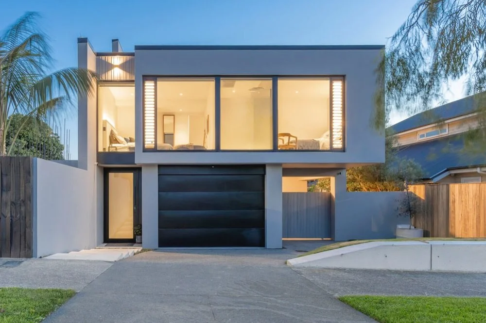 A sharp street elevation built around symmetry, defined architectural lines, and a seamless transition between concrete, plaster and glass.