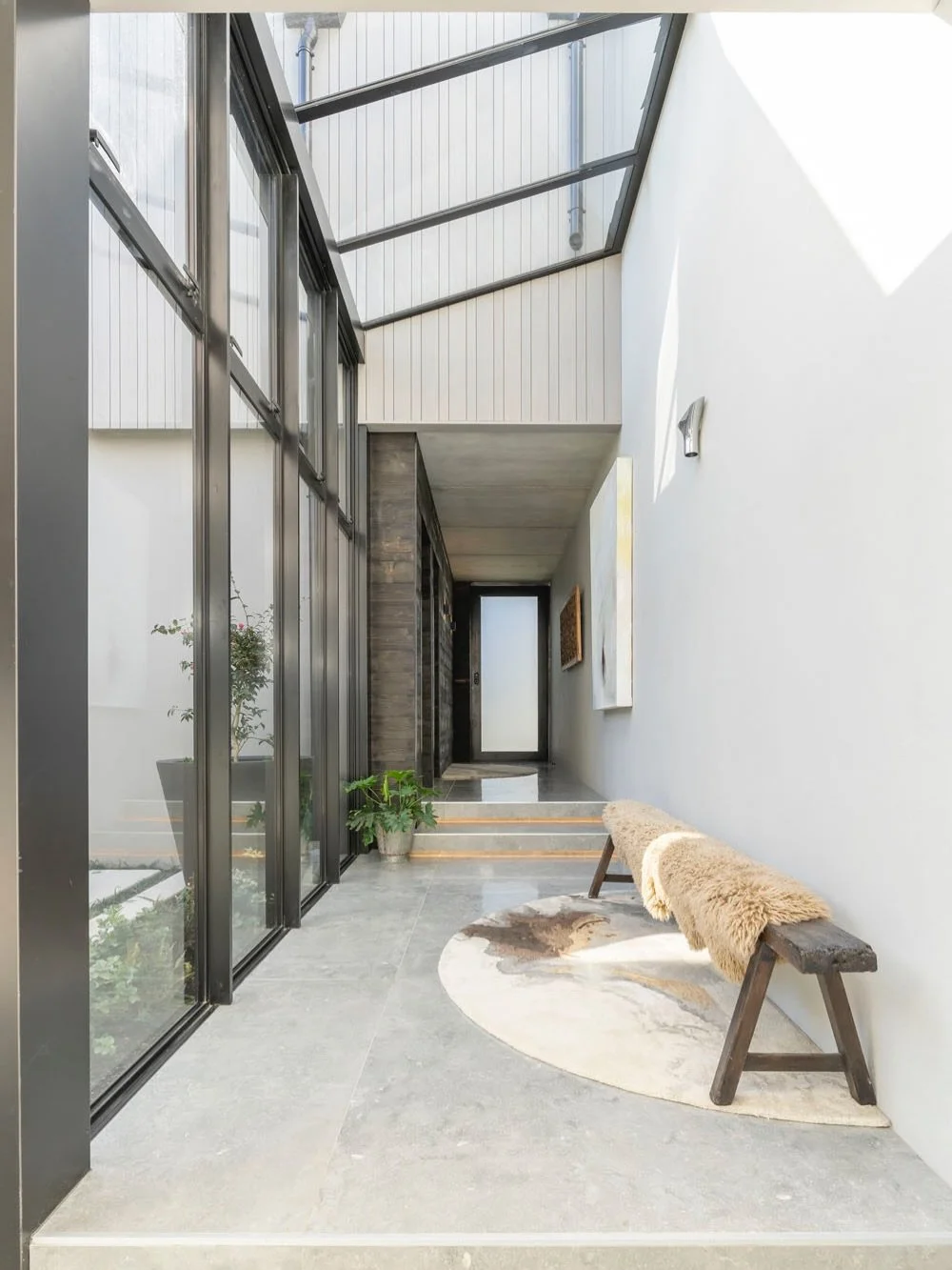 The atrium brings a sense of modern elegance, defined by skylit spaces and clean lines that carry through the heart of this home.