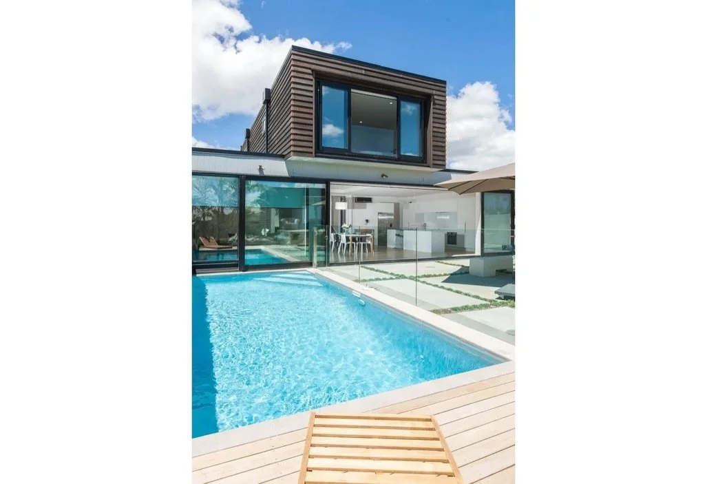Cedar weatherboards across both buildings, with the pool and outdoor spaces working seamlessly together, and the below ground garage neatly integrated under the out-house
