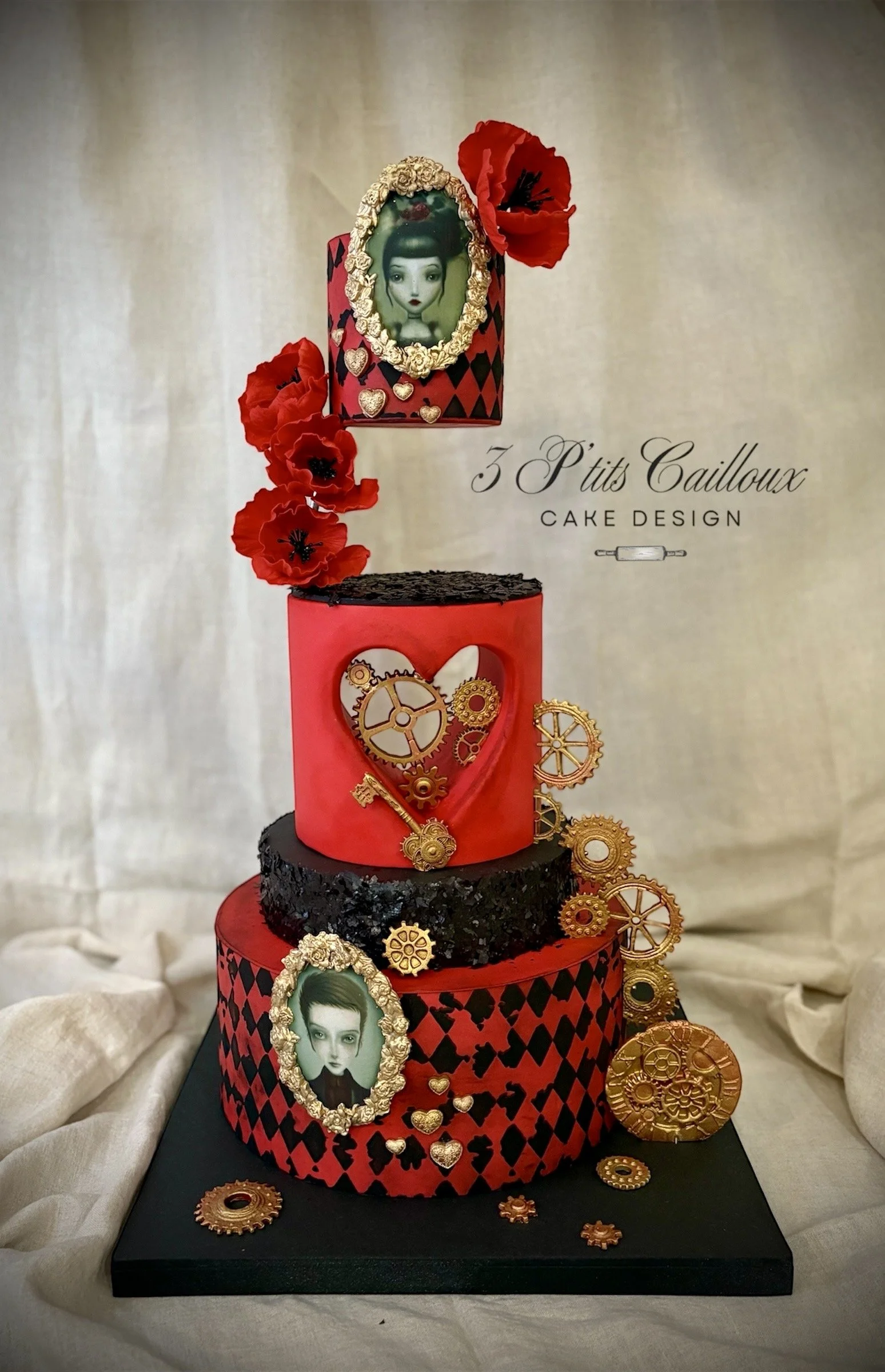 Gâteau à plusieurs niveaux avec des éléments décoratifs rouges et noirs, des portraits encadrés, des fleurs rouges, des engrenages en or, et le texte "3 P'tits Cailloux Cake Design".