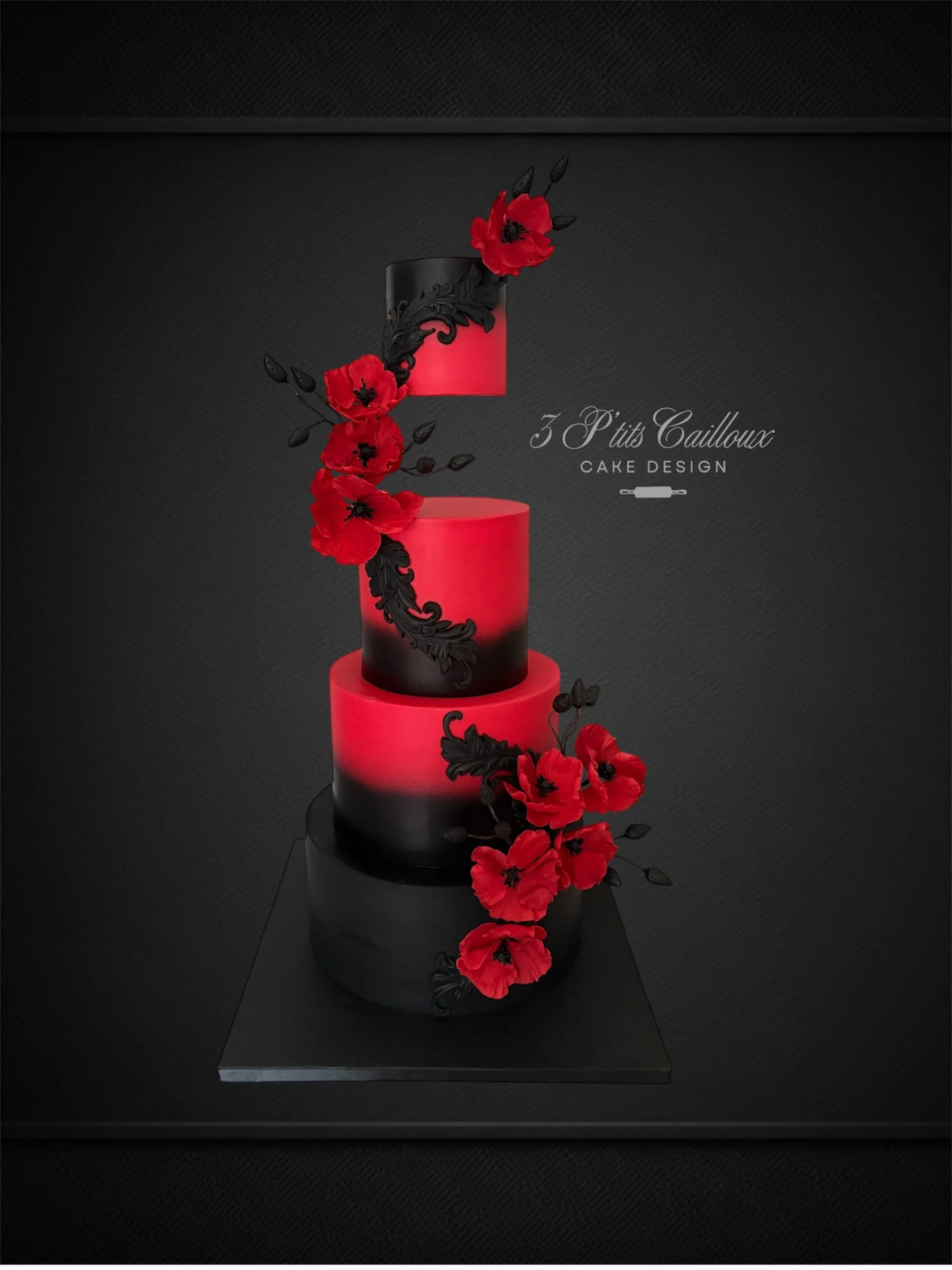 Gâteau à trois étages avec une décoration de fleurs rouges et d'ornements noirs, exposé sur une plateforme noire.