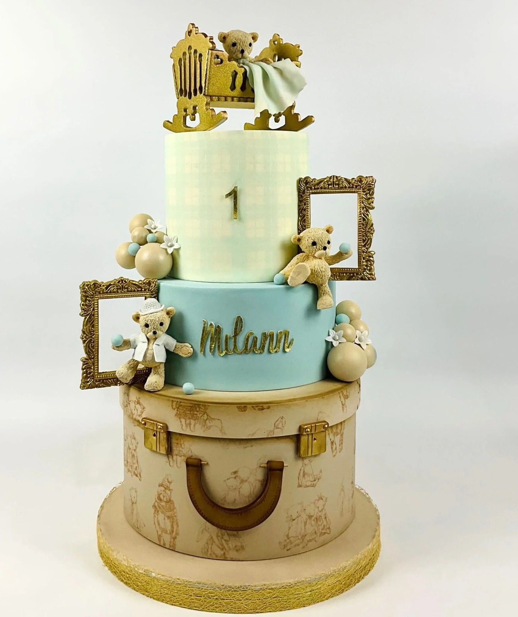 Gâteau d'anniversaire à trois étages avec des ours en peluche, des cadres dorés, des boules blanches et bleues, et une inscription 'Milann'.