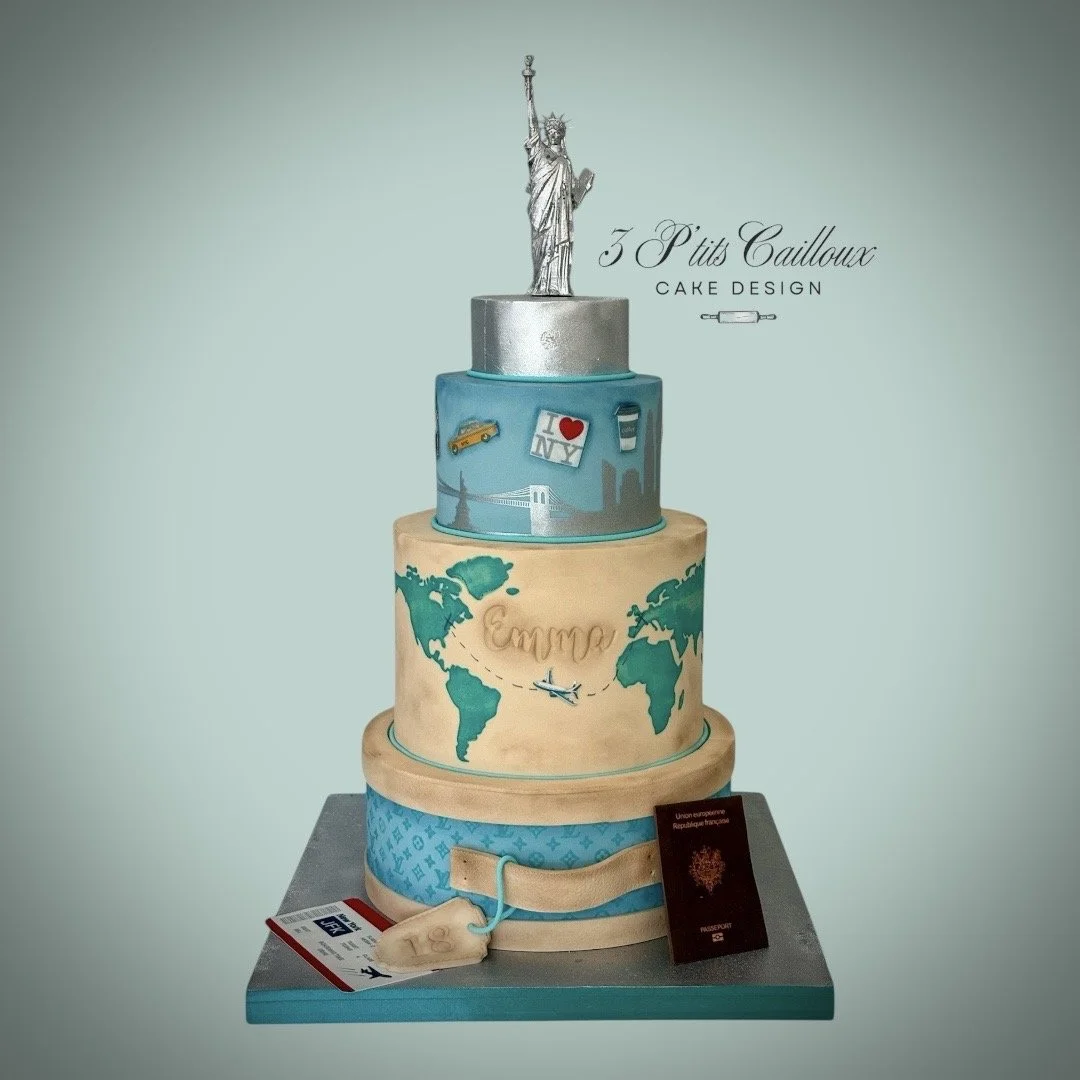 Gâteau en forme de trois niveaux avec un thème voyage et New York, décoré avec la Statue de la Liberté en haut, symboles de New York sur le deuxième niveau, et une carte du monde avec un avion sur le troisième, avec un passeport et une valise en dessous.