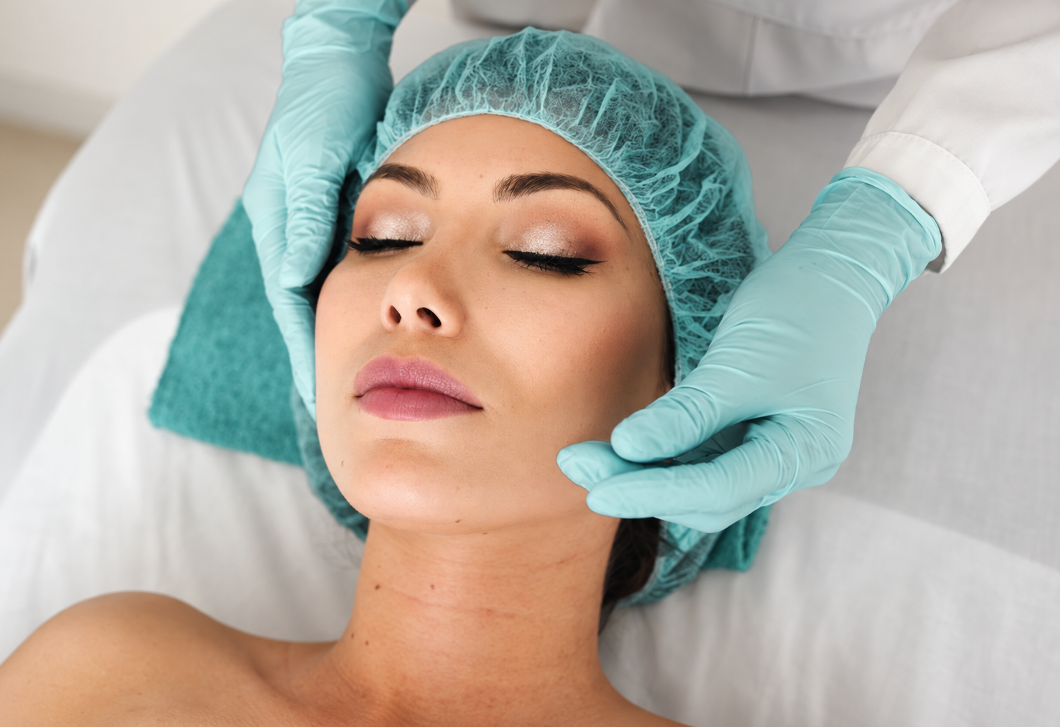 Woman receiving a facial aesthetic treatment from a practitioner wearing gloves.