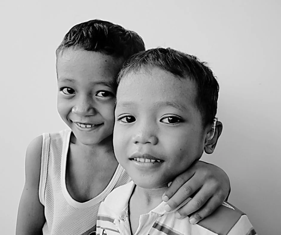 Two young boys smiling, one with his arm around the other, in black and white photo.