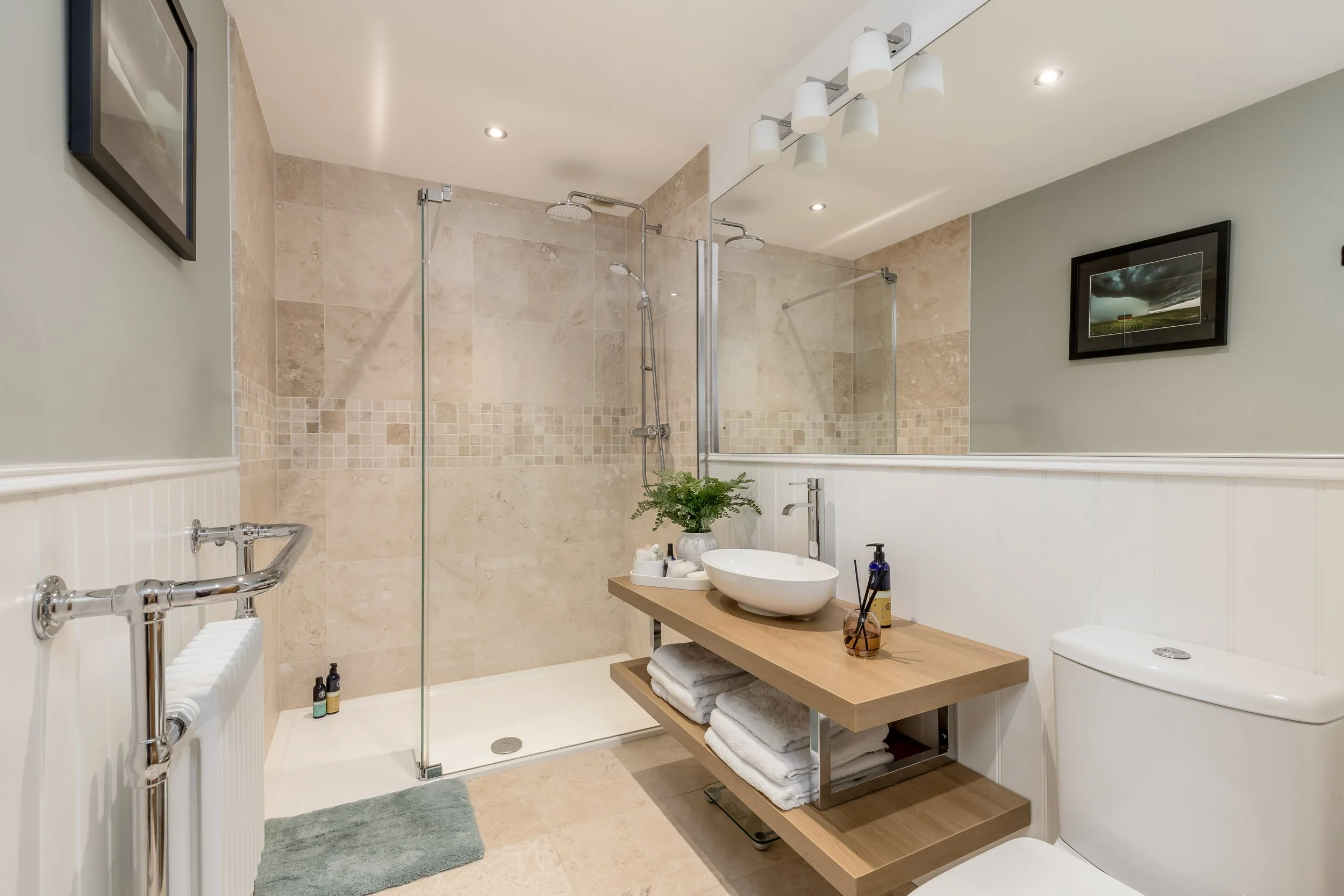 Bathroom with a walk-in shower, a wooden vanity with a vessel sink, a white toilet, a framed photo on the wall, and a mirror above the sink.