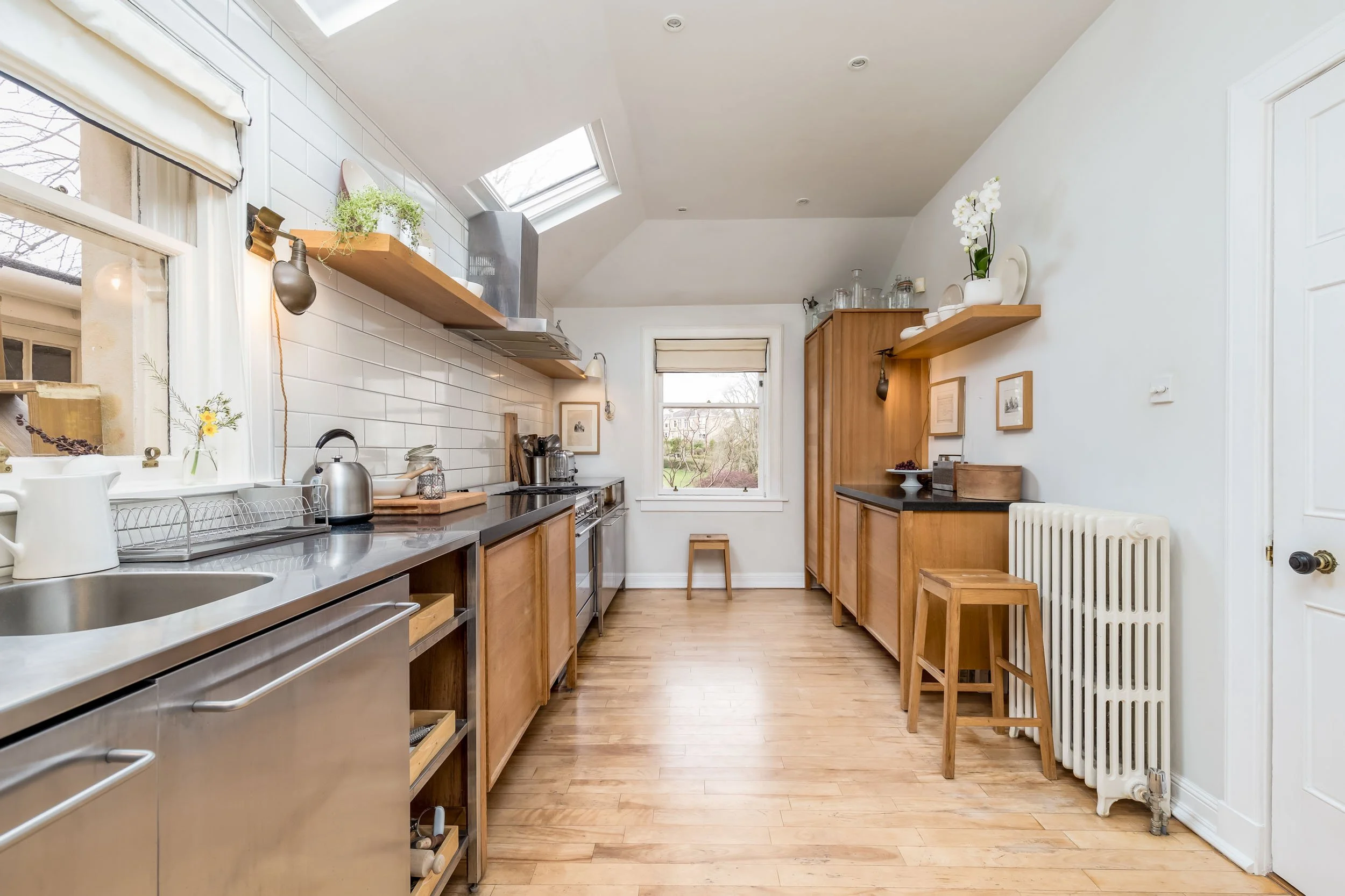 Bright kitchen with wooden cabinets, white walls, skylights, and hardwood floors.