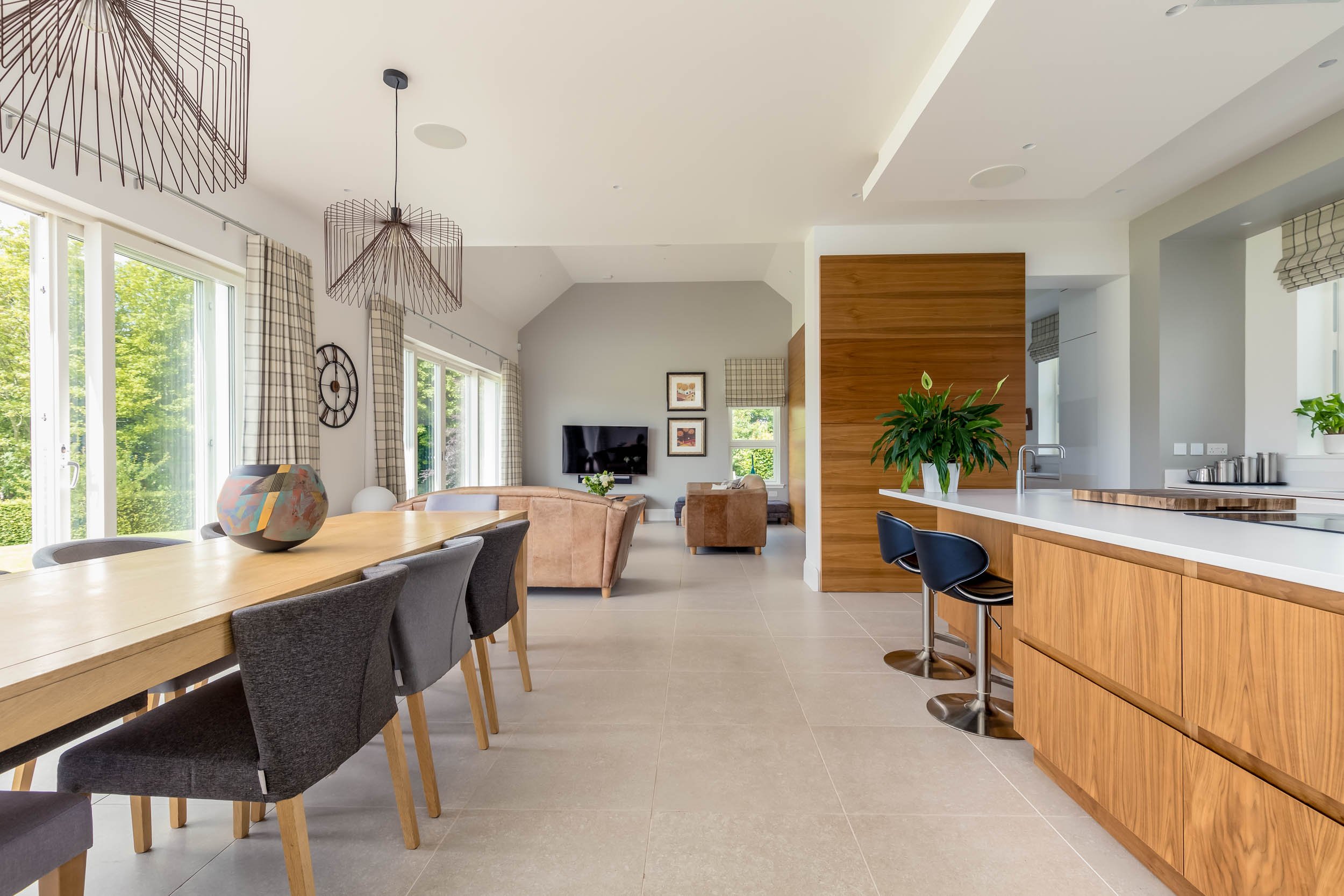 Open-concept living and dining area with large windows, wooden furniture, and modern decor.