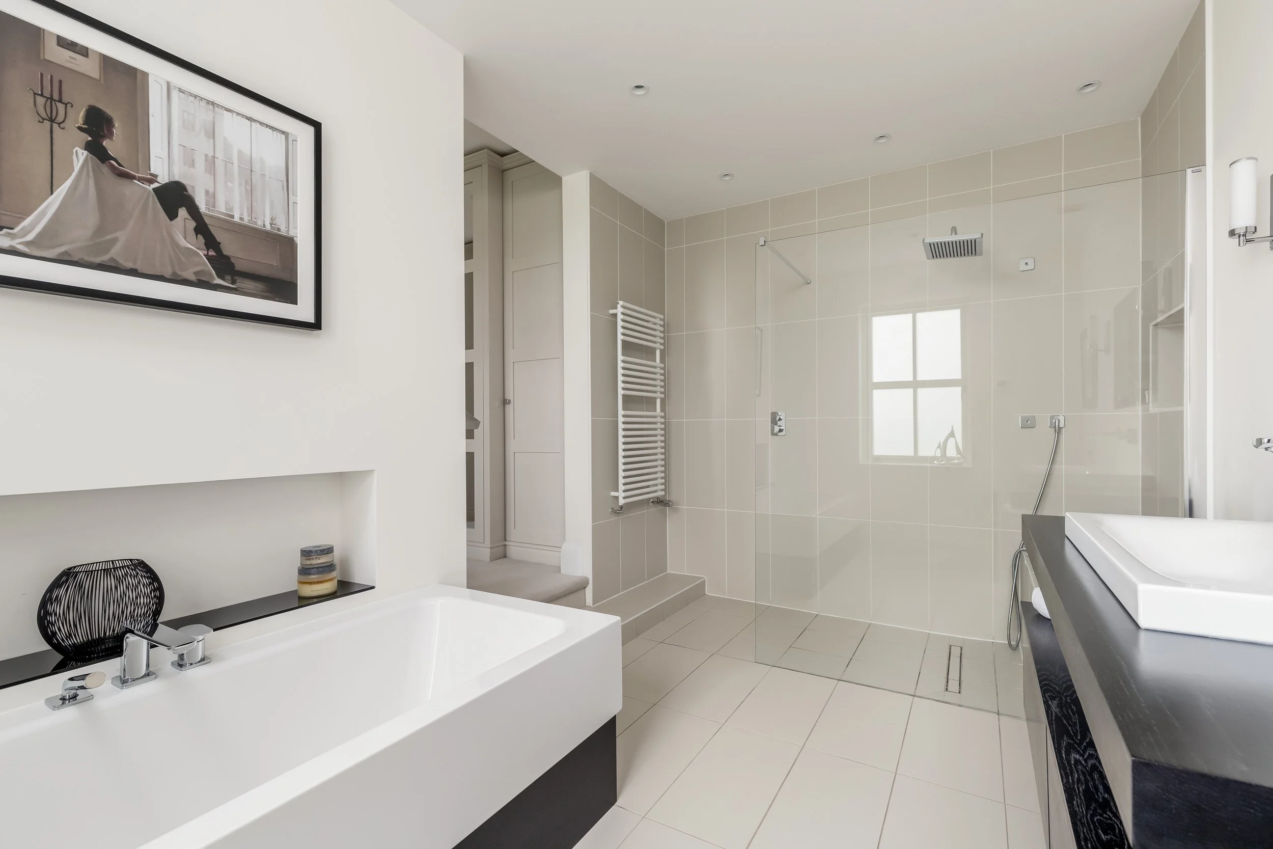 Modern bathroom with a large walk-in shower, a white bathtub, a black countertop with a rectangular vessel sink, and a framed art piece of a girl in a white dress sitting on a window sill.