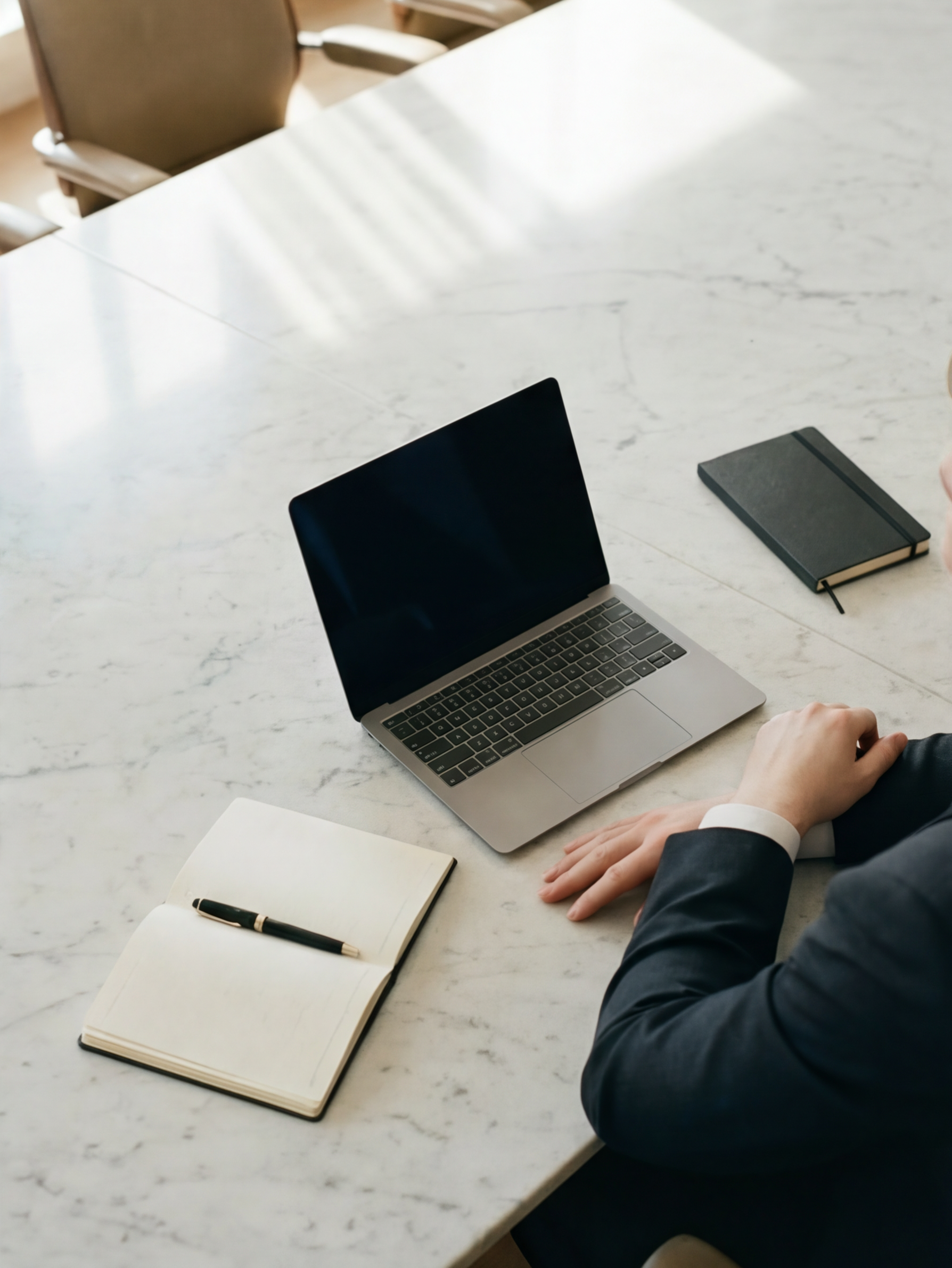 An open laptop and a paper notebook on an marble table