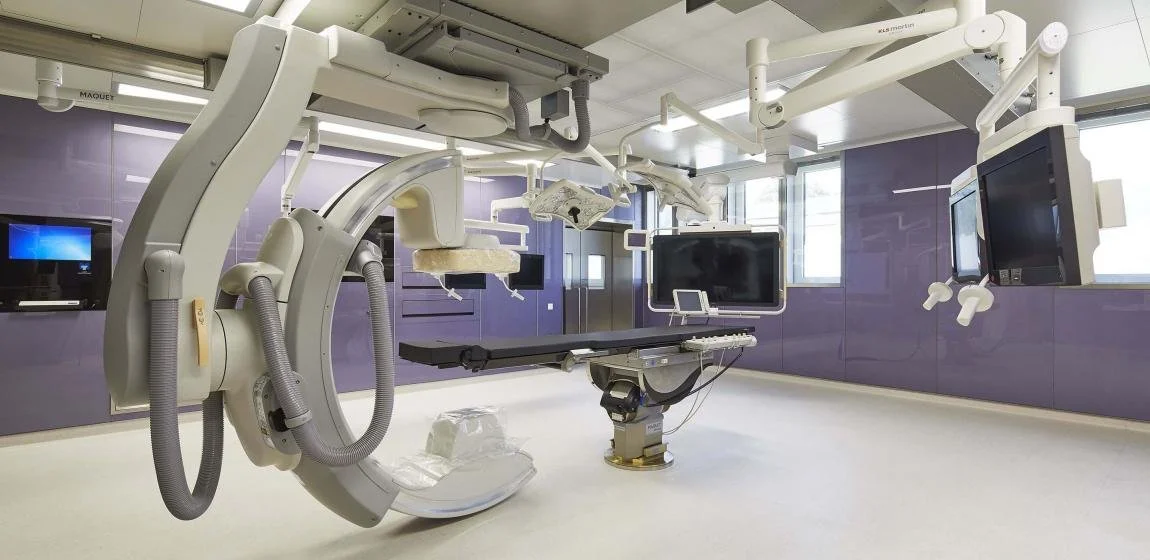Ein Operationssaal mit medizinischer Ausrüstung, einschließlich CT-Scanner, Überwachungsmonitore und chirurgischen Geräten.