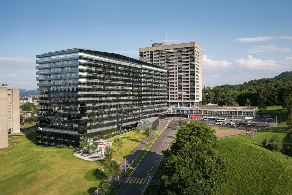 Mehrstöckige Bürogebäude in einer städtischen Umgebung mit grünen Parks und Straßen