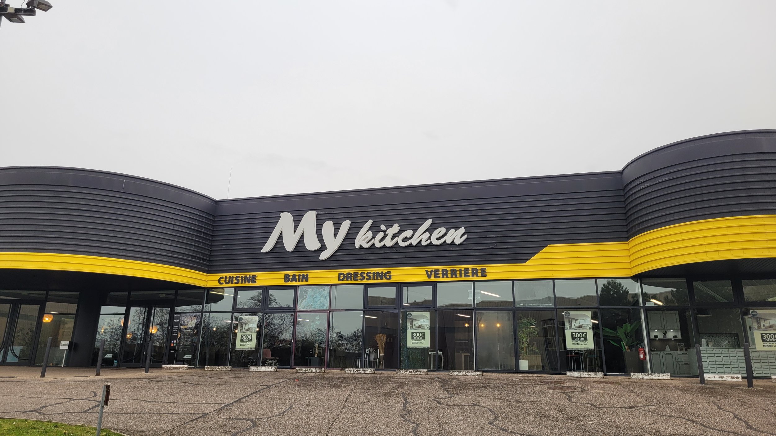Façade d'un magasin nommé 'My kitchen' avec une enseigne en jaune indiquant les sections : Cuisine, Bain, Dressing, Verrière.