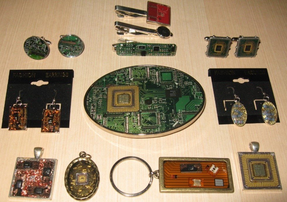 Collection of electronic circuit boards and jewelry, including earrings and pendants, arranged on a wooden surface.