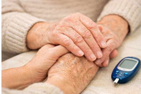 A person's hand holding an elderly person's hand, with a blood glucose meter nearby, suggesting diabetes care.
