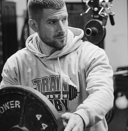 A man working out in a gym, lifting a weight plate.