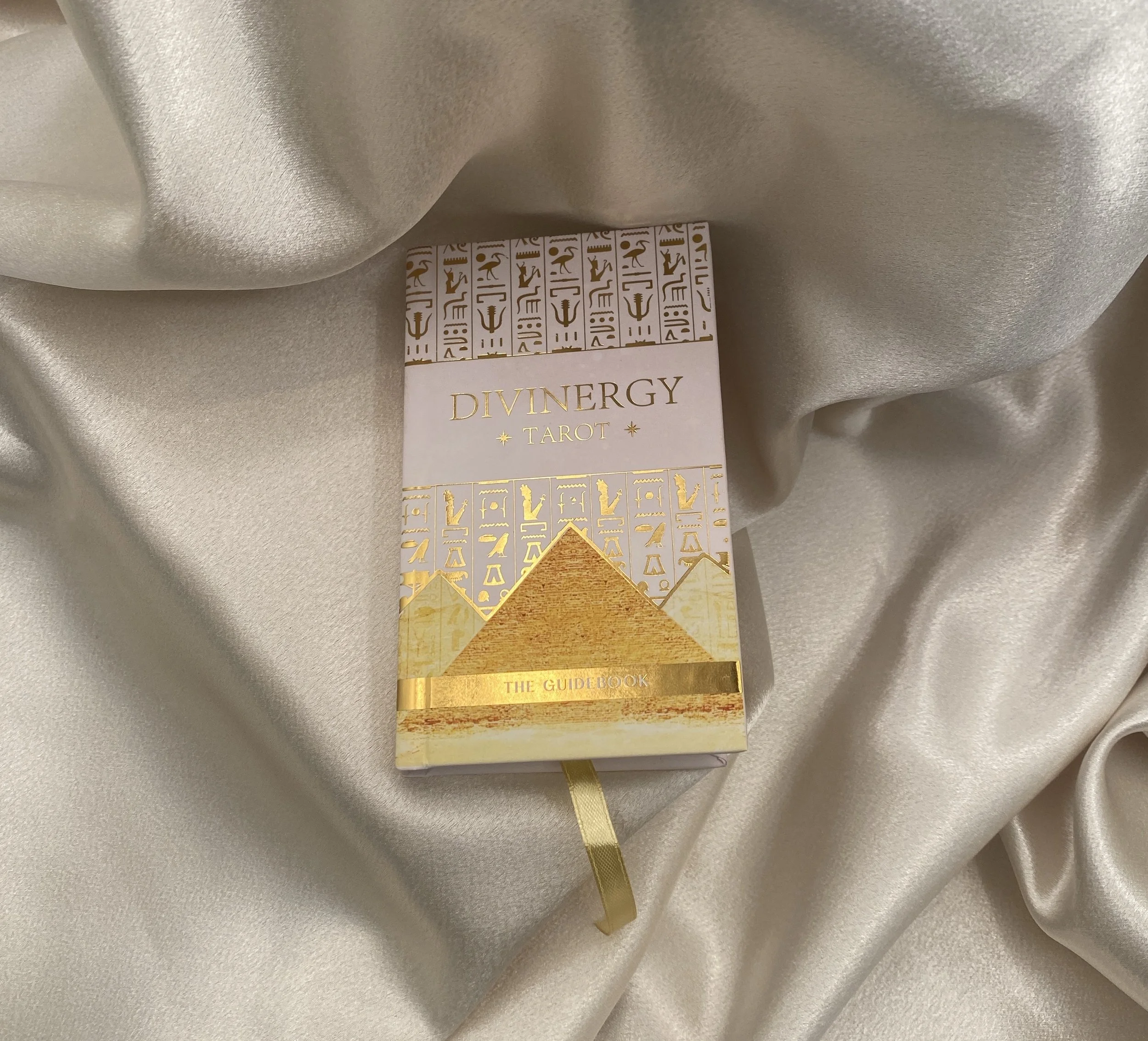 A deck of Divinergy Tarot cards resting on a cream-colored satin fabric.