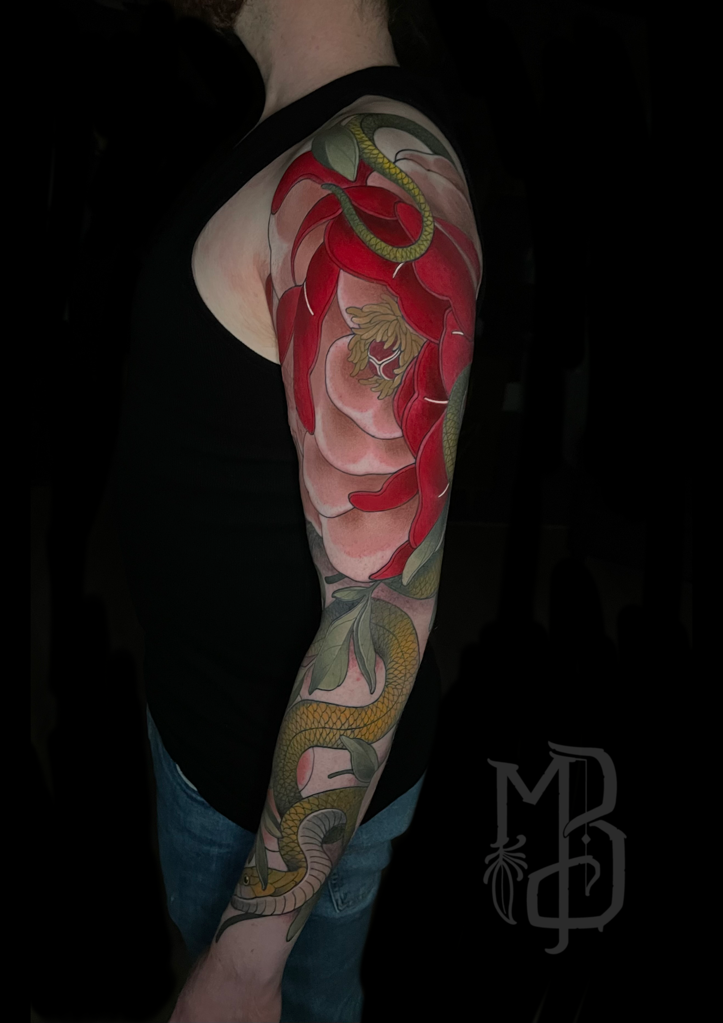 Tattoo sleeve  done in full colour, in neotraditional style, featuring a snake intertwined with large red and pink peony flowers, green leaves, and detailed shading on the arm of a person.