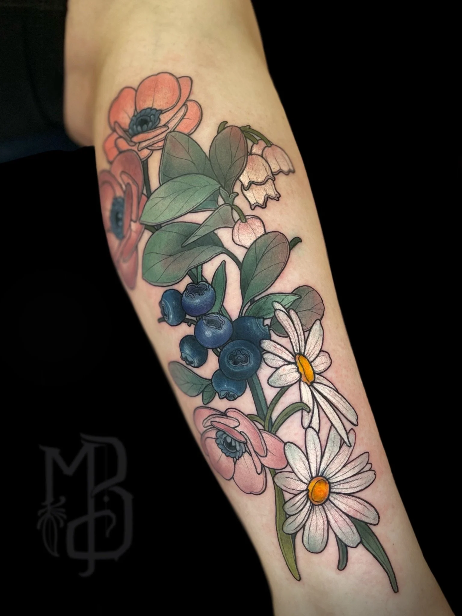 Colorful floral neotraditional tattoo featuring pink poppies, white daisies with yellow centers, blue berries, and green leaves on a person's leg.